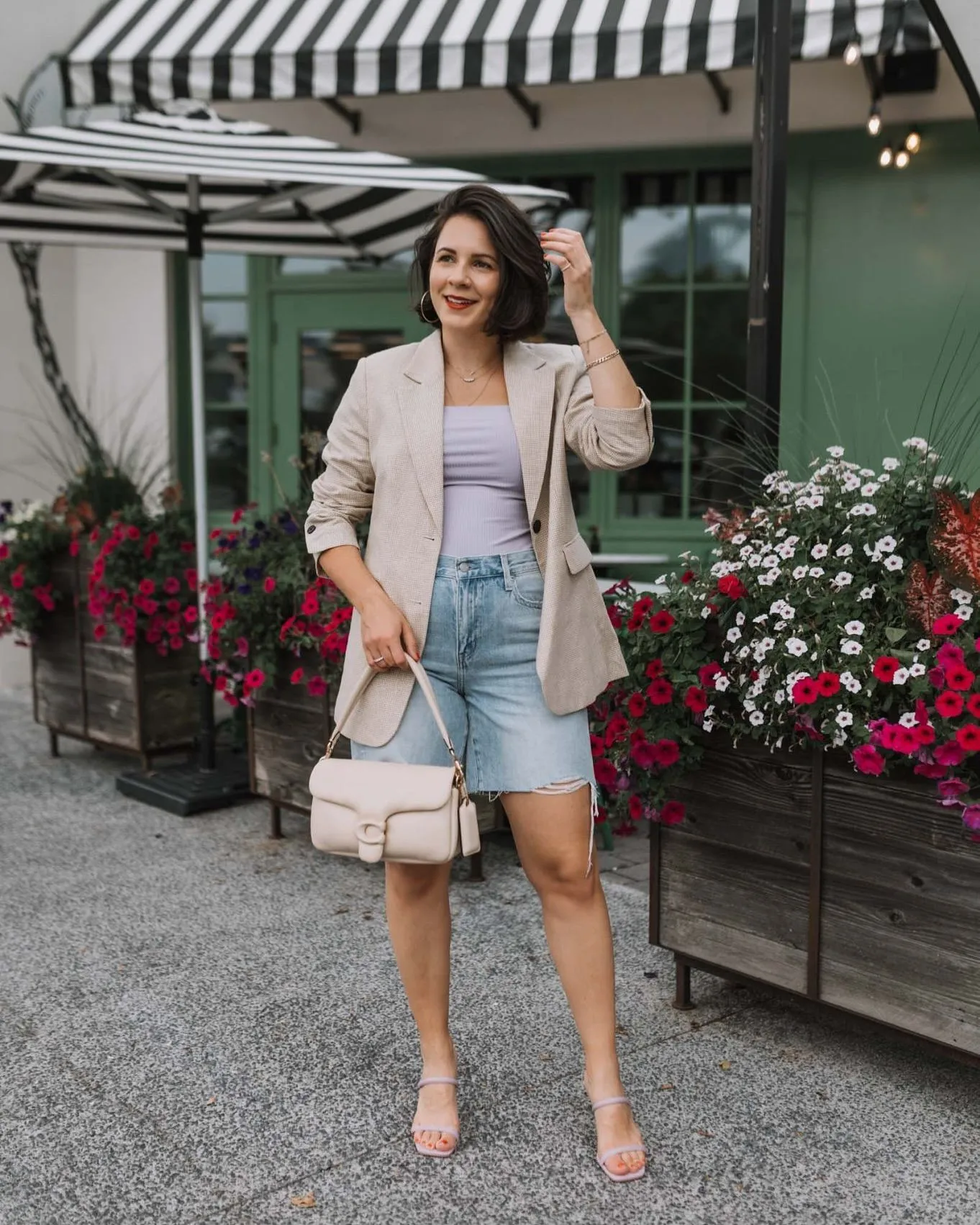 Close up of rolled sleeves on a peach oversized blazer with gold accessories