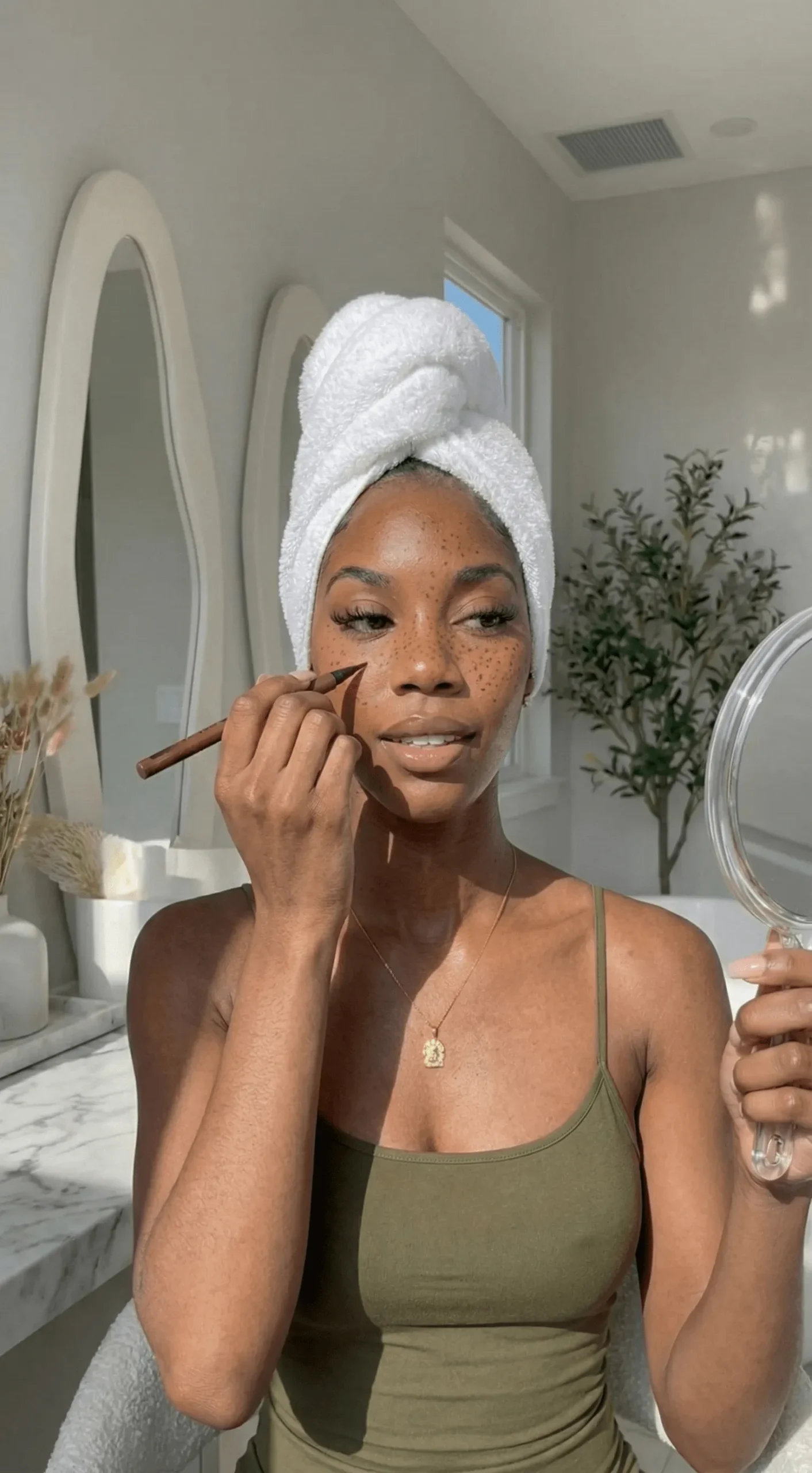 Model with dark skin applying faux freckles with liner