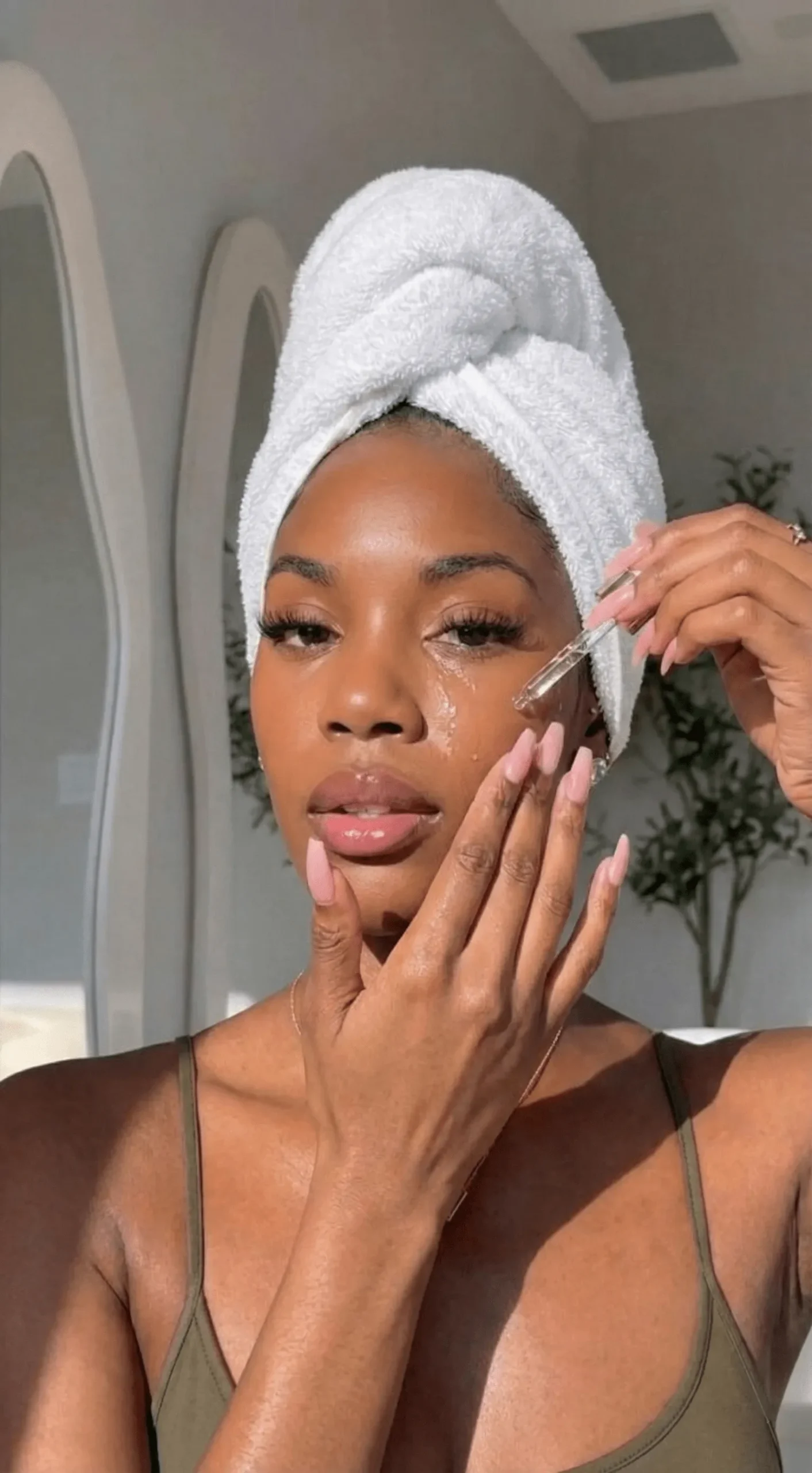 Model applying hydrating serum to deep skin tone for glazed finish