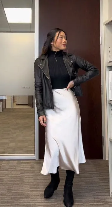 Woman wearing a black cropped leather jacket and champagne satin slip skirt