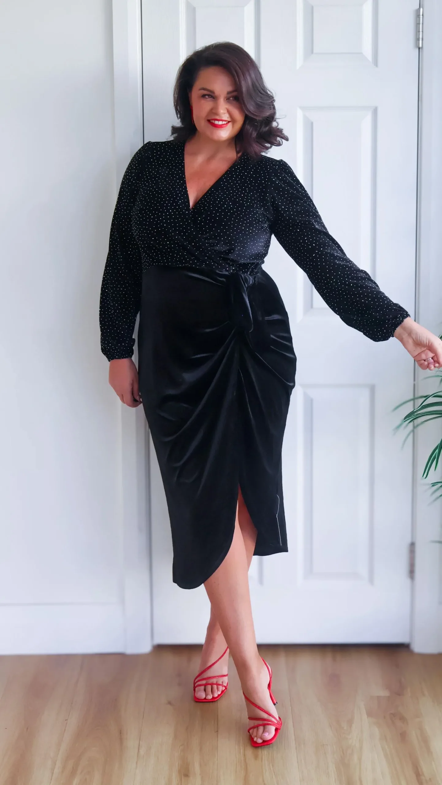 Plus size model wearing a black velvet wrap dress for a romantic evening look