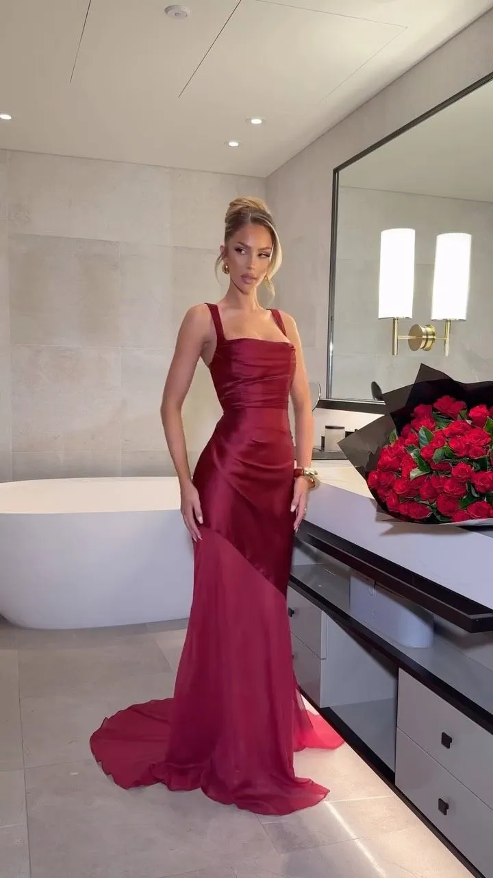 Woman wearing a deep burgundy silk slip dress in a dark romantic setting