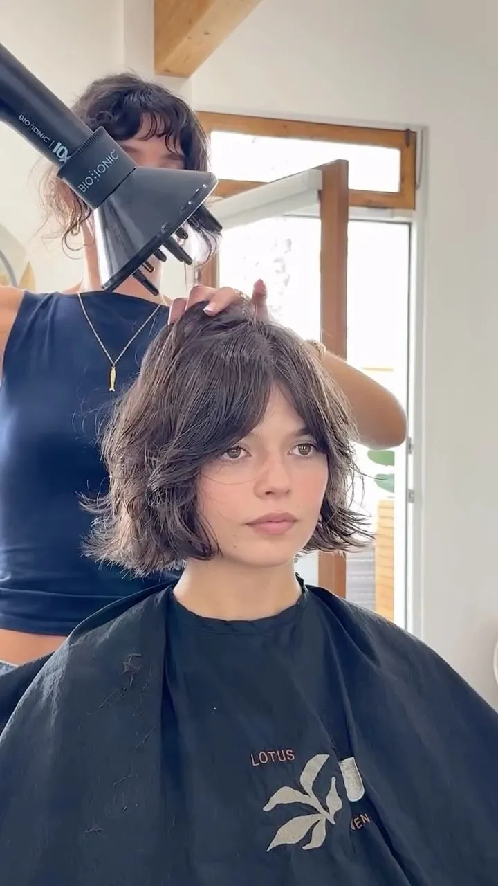 Woman styling a choppy bob haircut using a diffuser for root volume