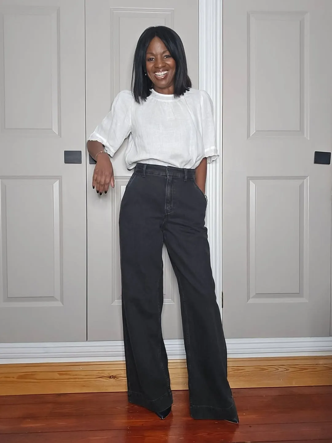 Woman demonstrating the French tuck with an oversized sweater and high waisted trousers