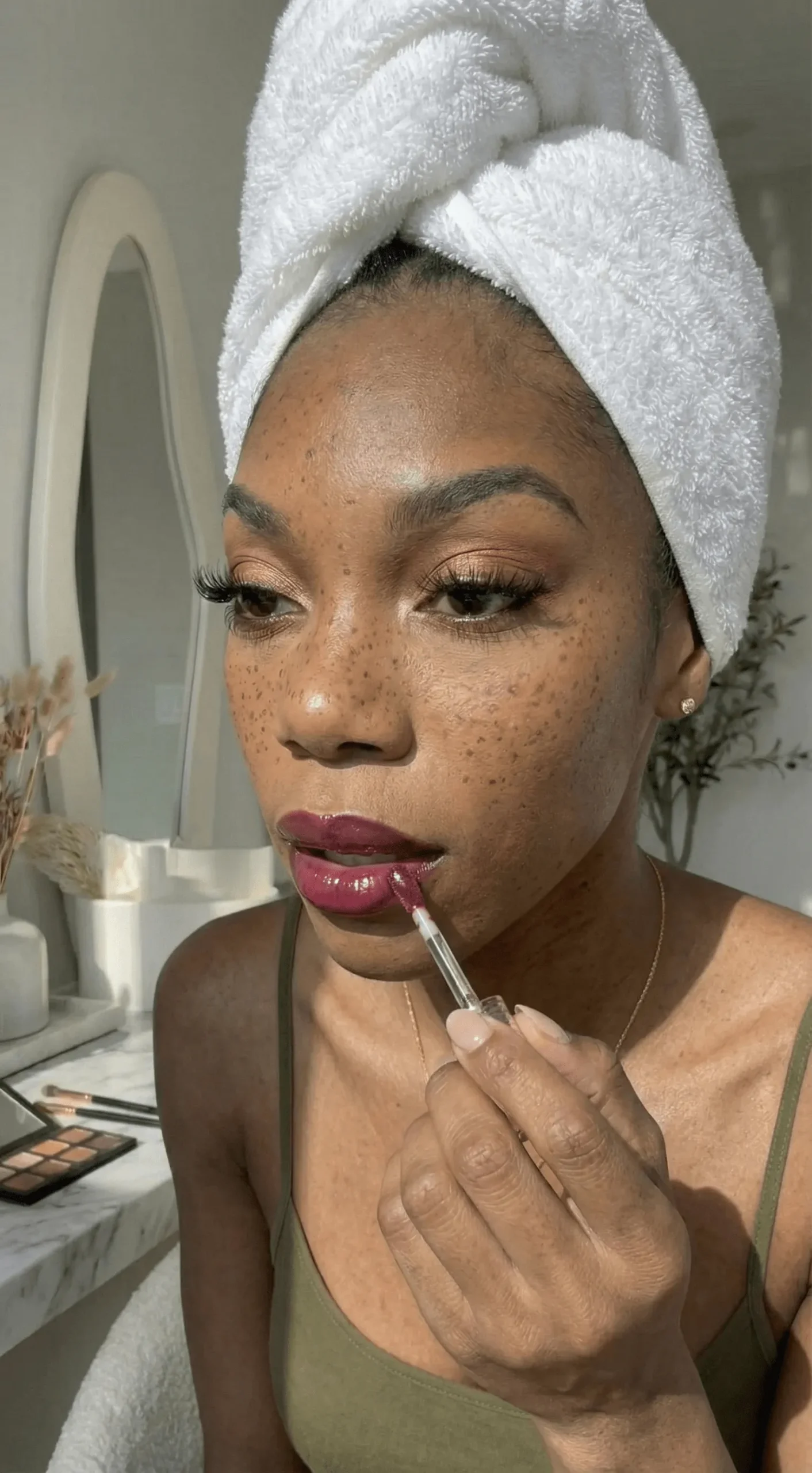 Close up of deep skin tone lips with glossy strawberry red lip oil application