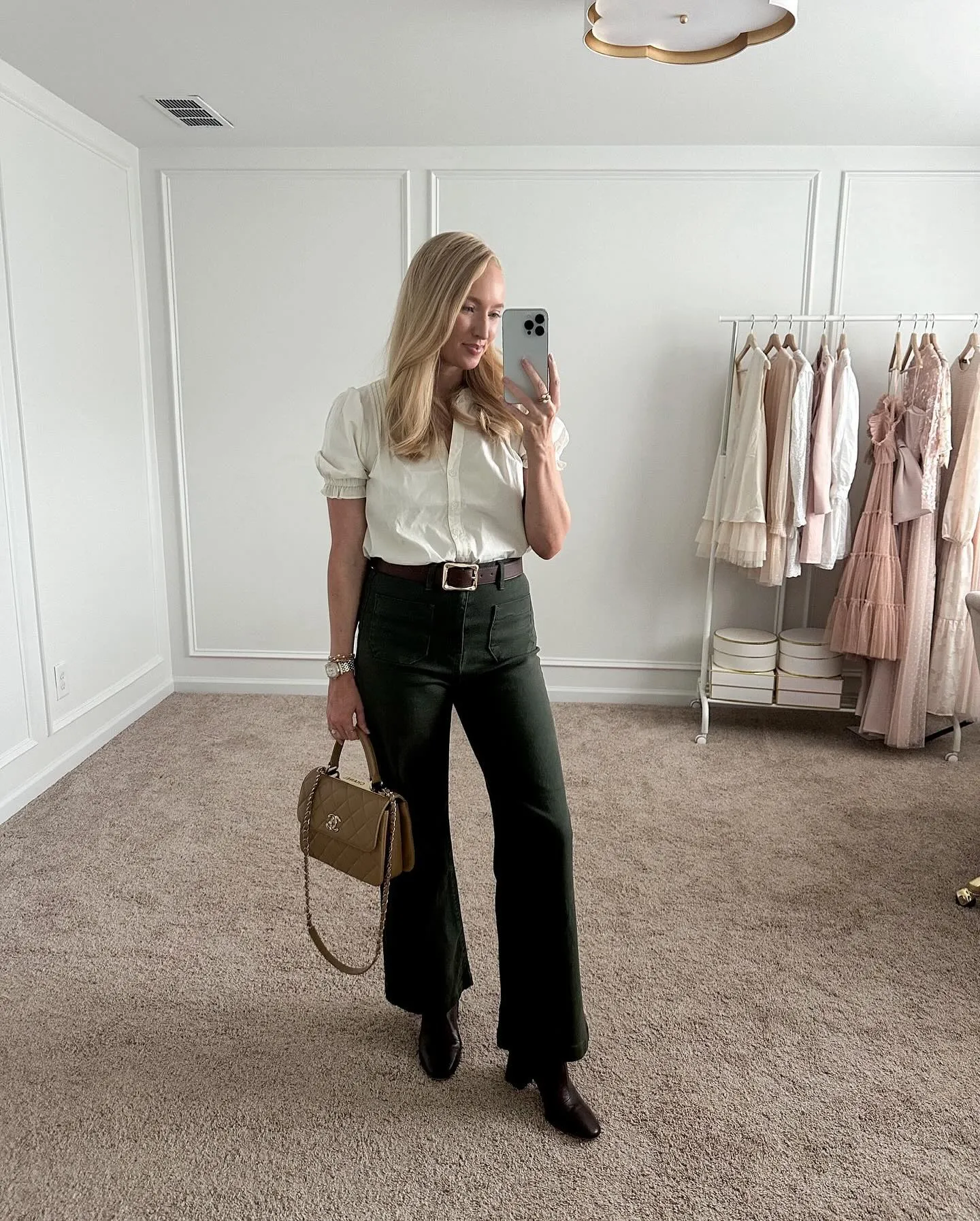 Petite woman styling high waisted indigo wide leg jeans with tucked white silk blouse