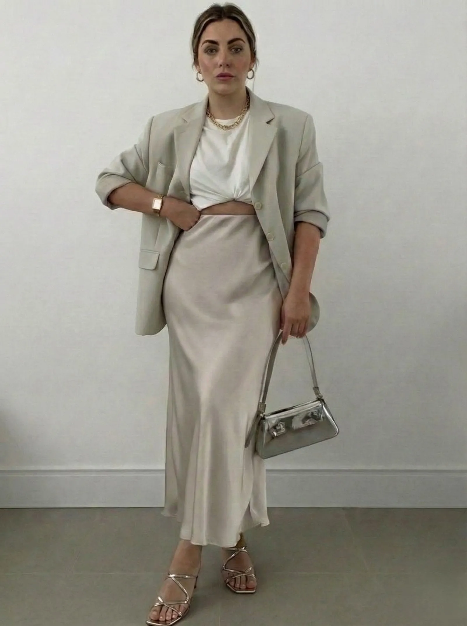 Woman with hourglass figure styling a knotted white tee with a champagne satin slip skirt