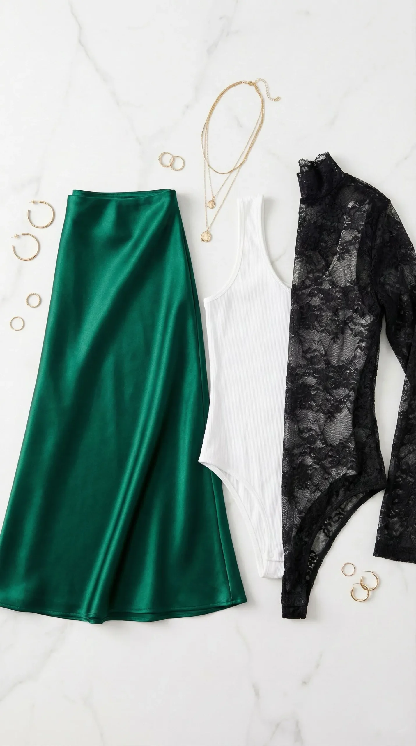 Flat lay of emerald satin skirt paired with white ribbed bodysuit and lace options