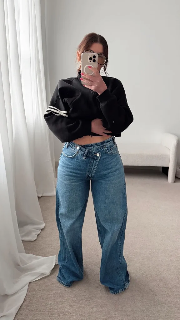 Petite woman wearing high waisted wide leg jeans with a fitted white crop top and sneakers