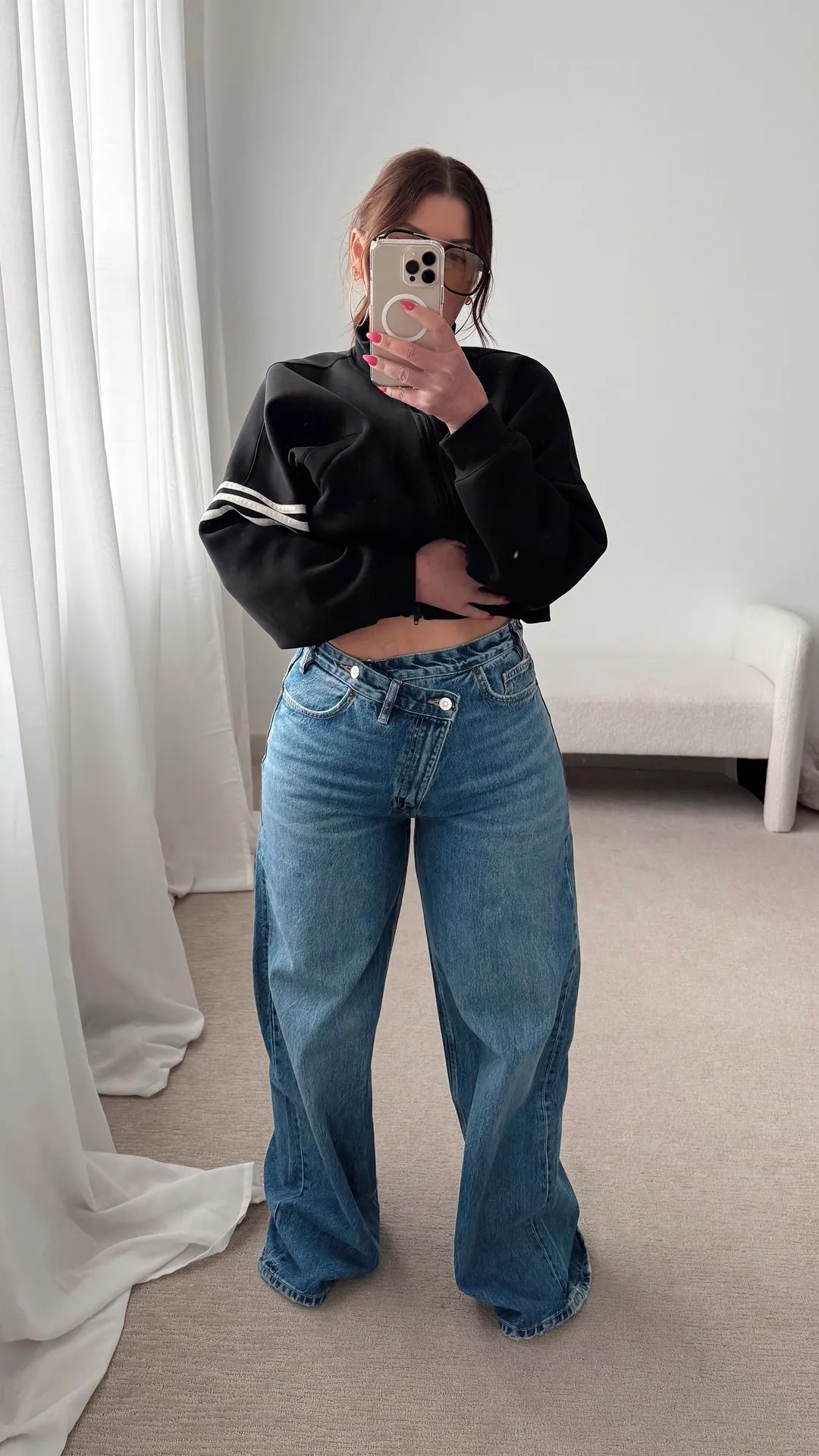 Petite woman wearing high waisted wide leg jeans with a fitted white crop top and sneakers