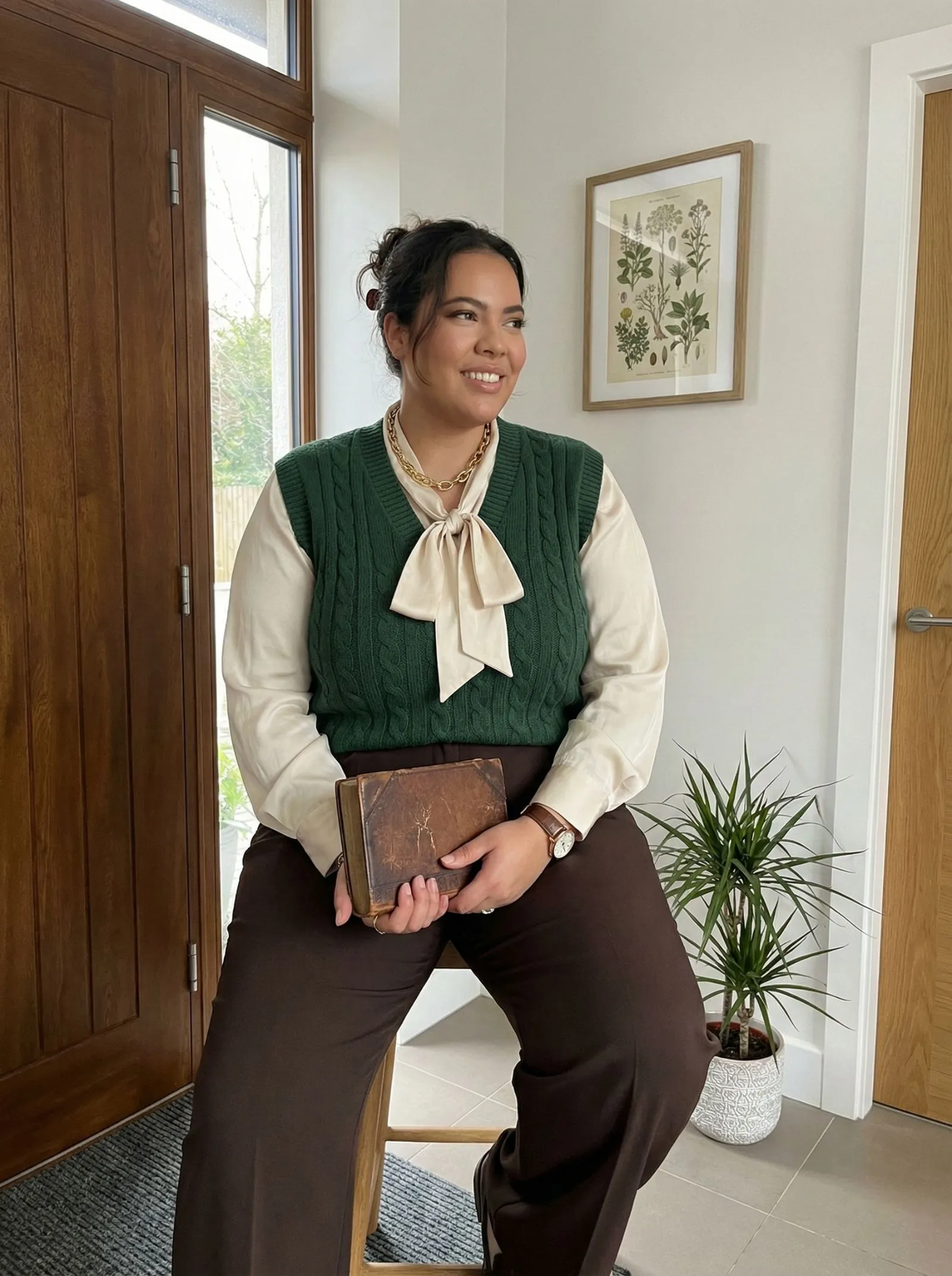 Plus size woman wearing a forest green knit vest and silk blouse in a library setting.
