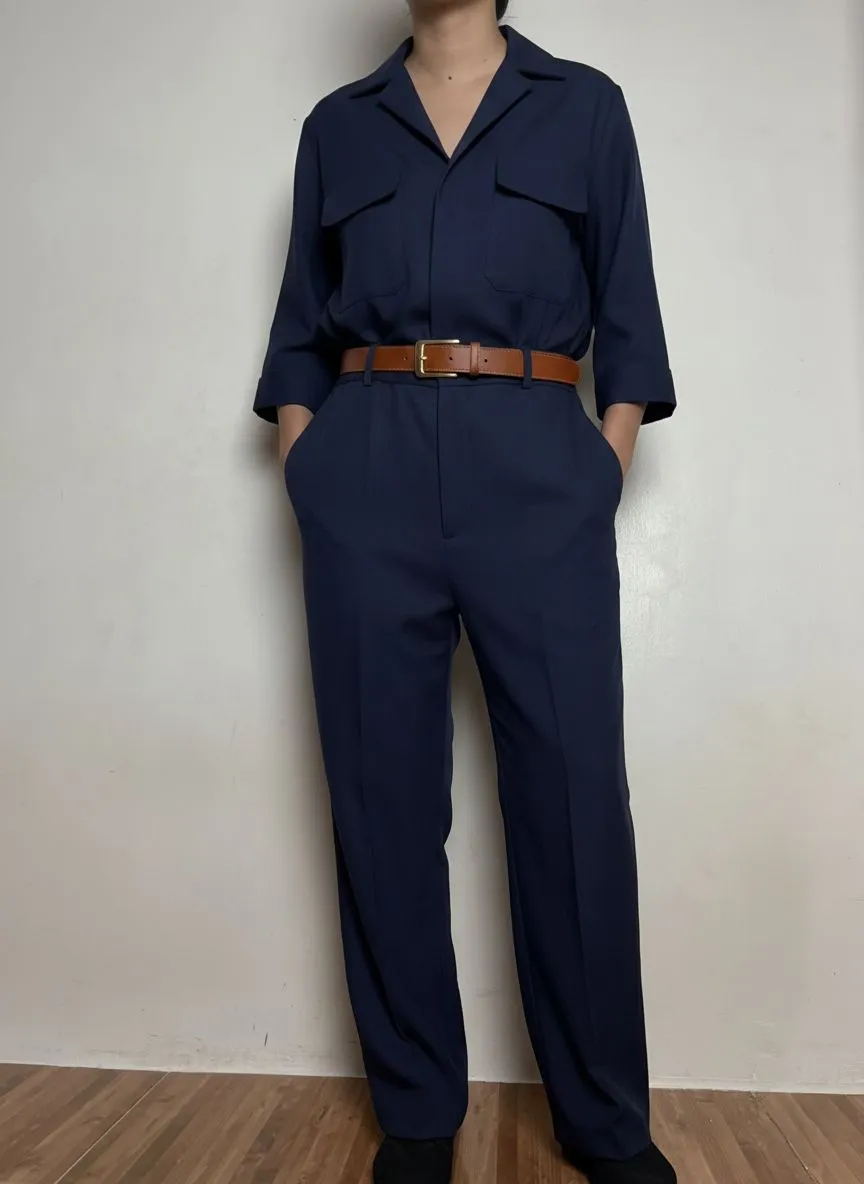 Woman in a tailored navy jumpsuit with a leather belt for professional workwear