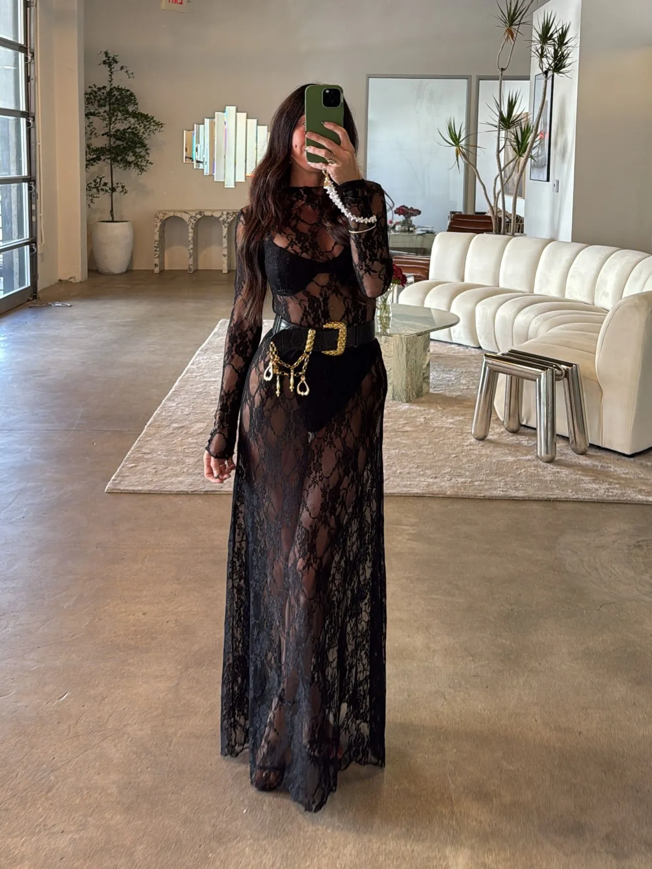 Model wearing a dramatic sheer black lace gown with floral embroidery for a dark romance look