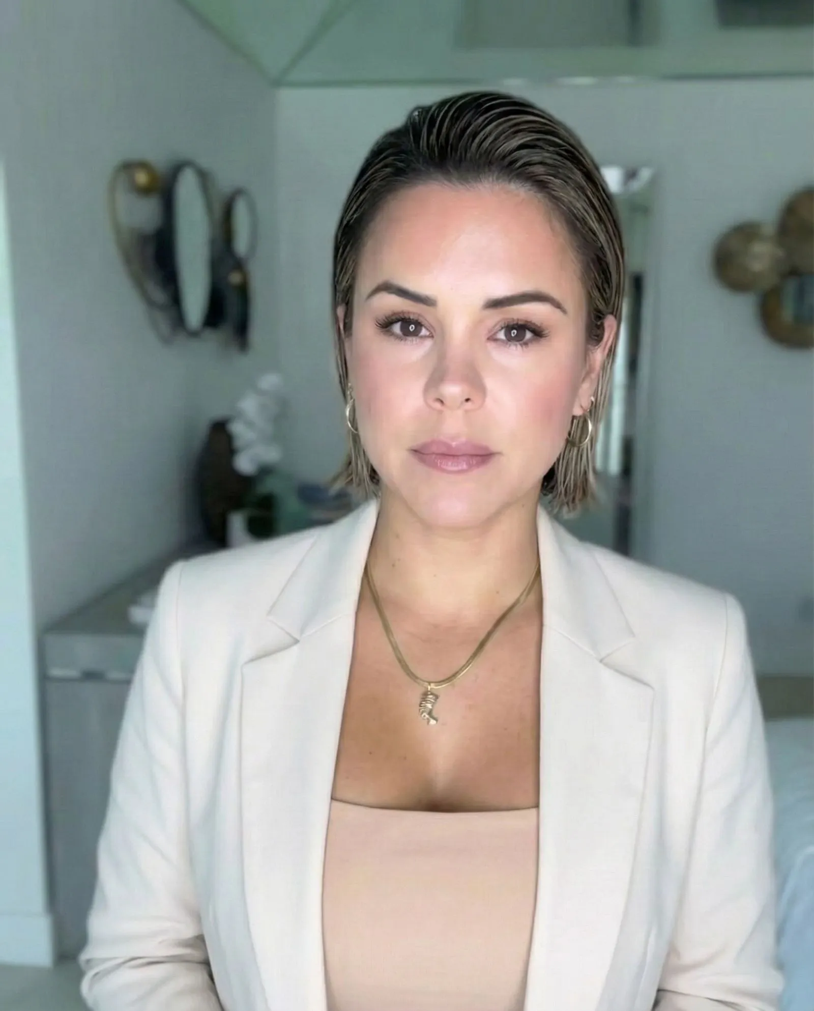 Model with slicked back wet look bob hairstyle wearing a black blazer