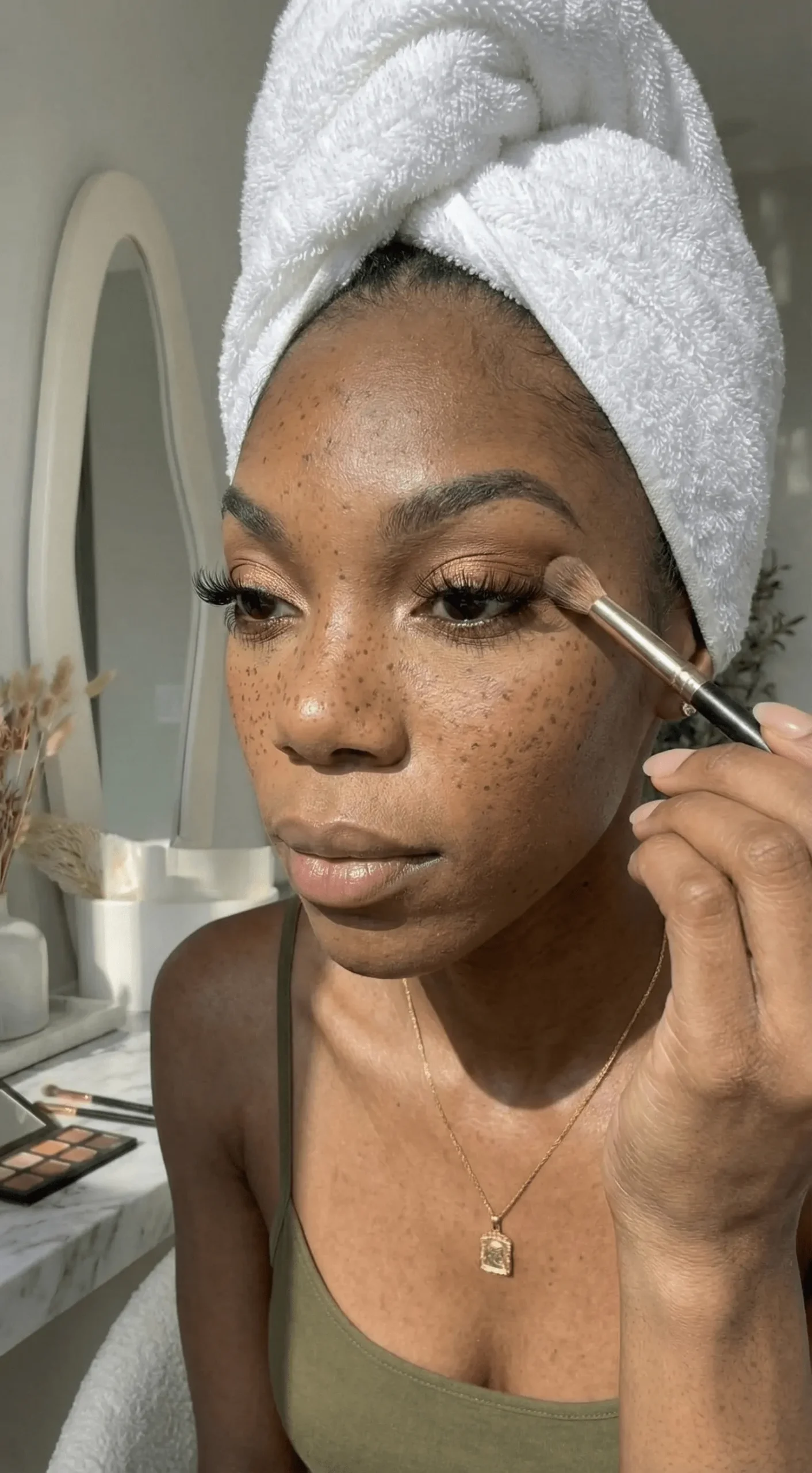 Close up of black woman wearing warm brown eyeshadow and volumizing mascara