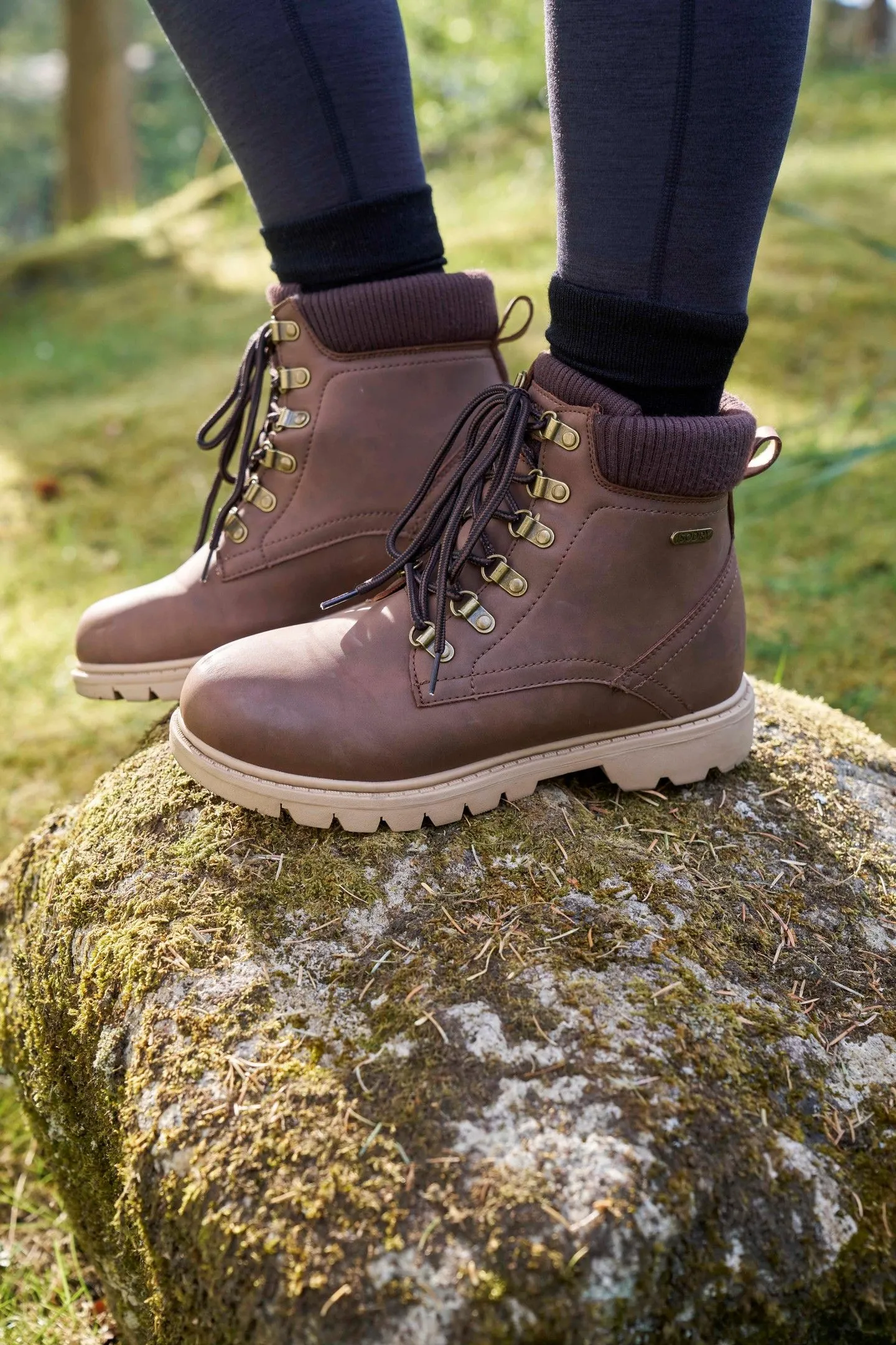 Stylish brown leather hiking boots walking on grey cobblestones in Switzerland