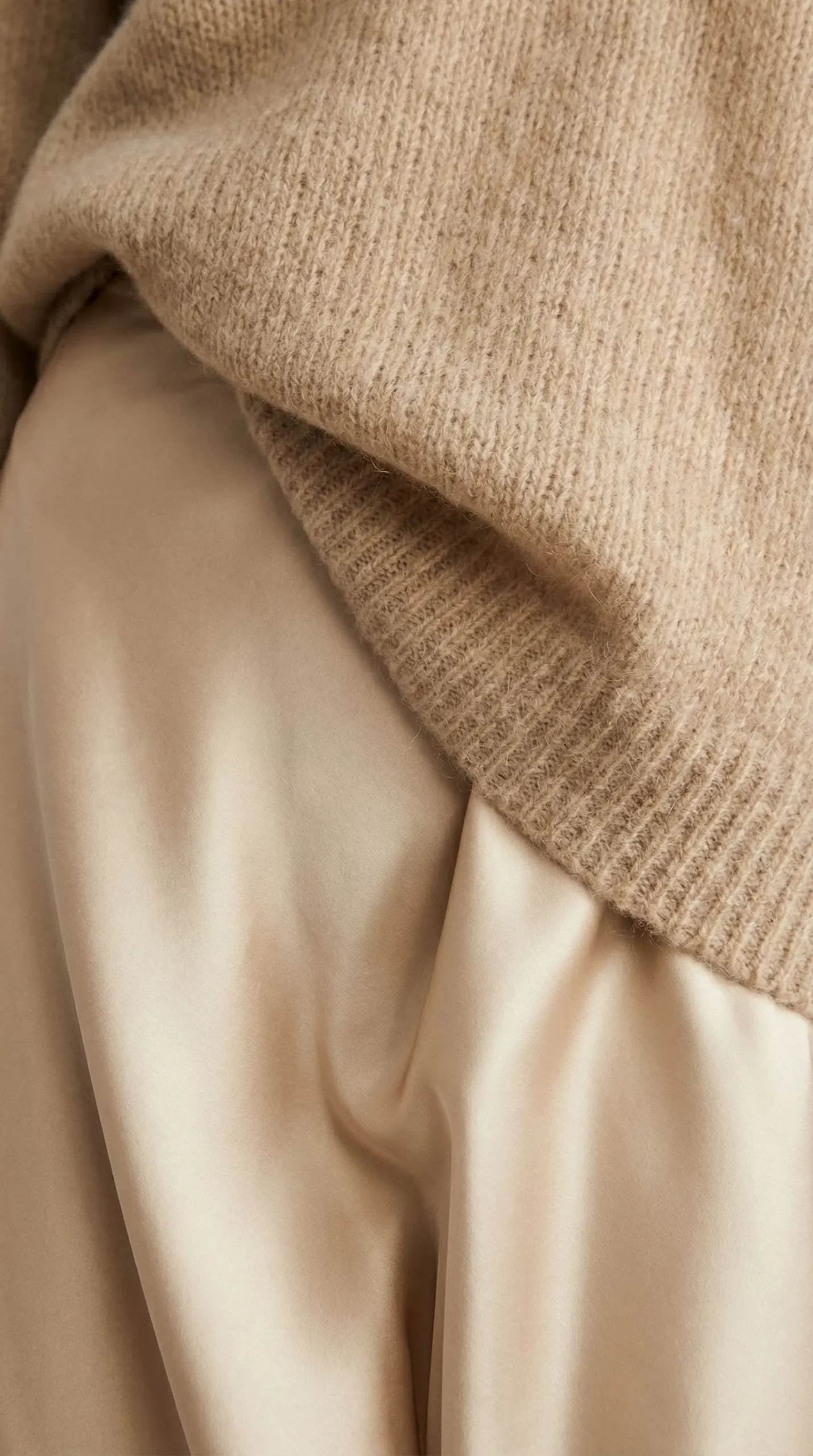 Close up detail of matte knit sweater against shiny satin fabric