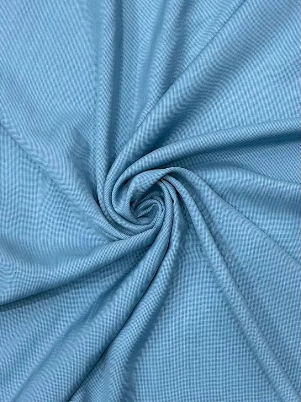 Close up texture of pale blue cotton sateen fabric with a pearl button