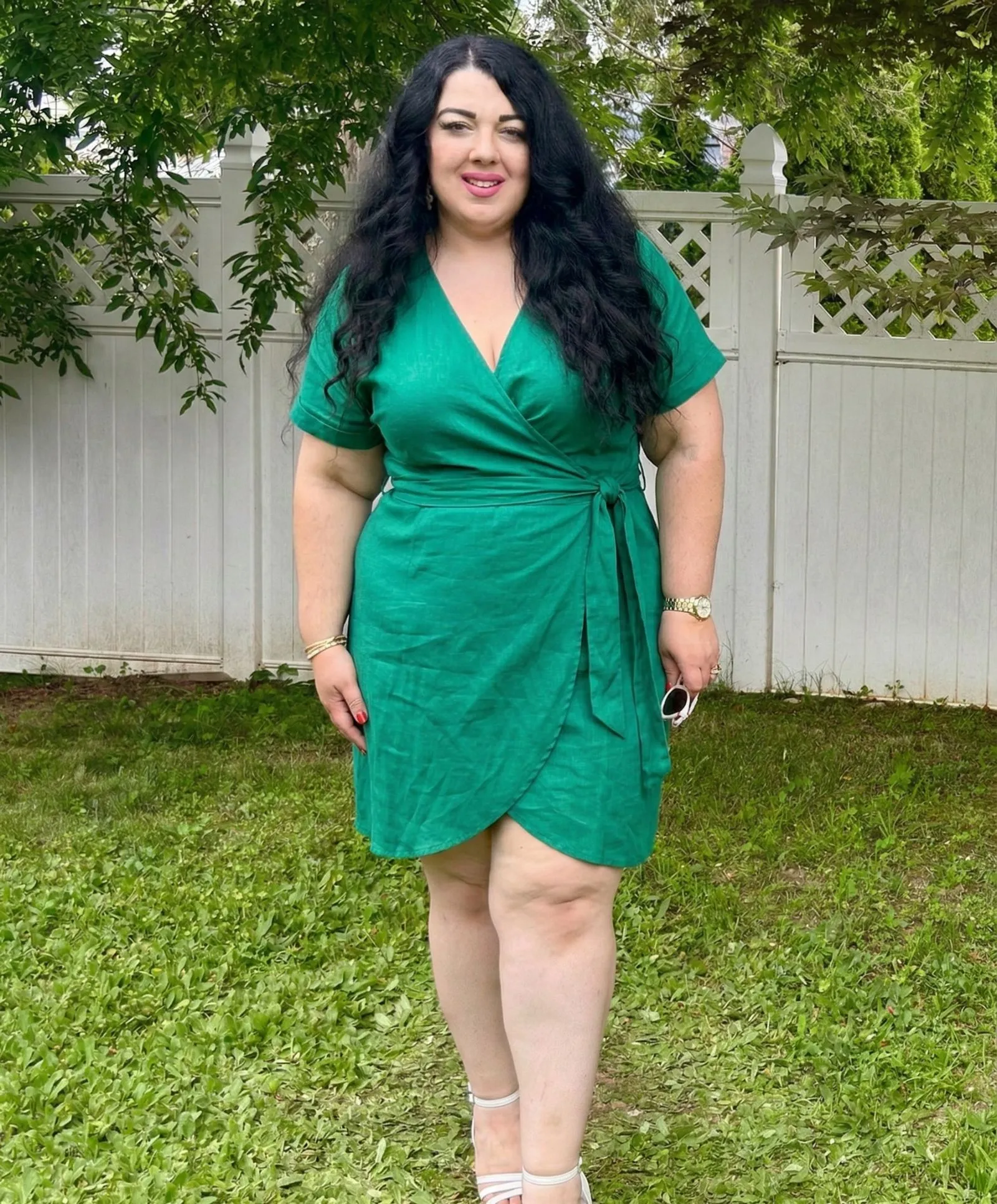 Plus size woman wearing a breathable emerald wrap dress for business casual summer workwear