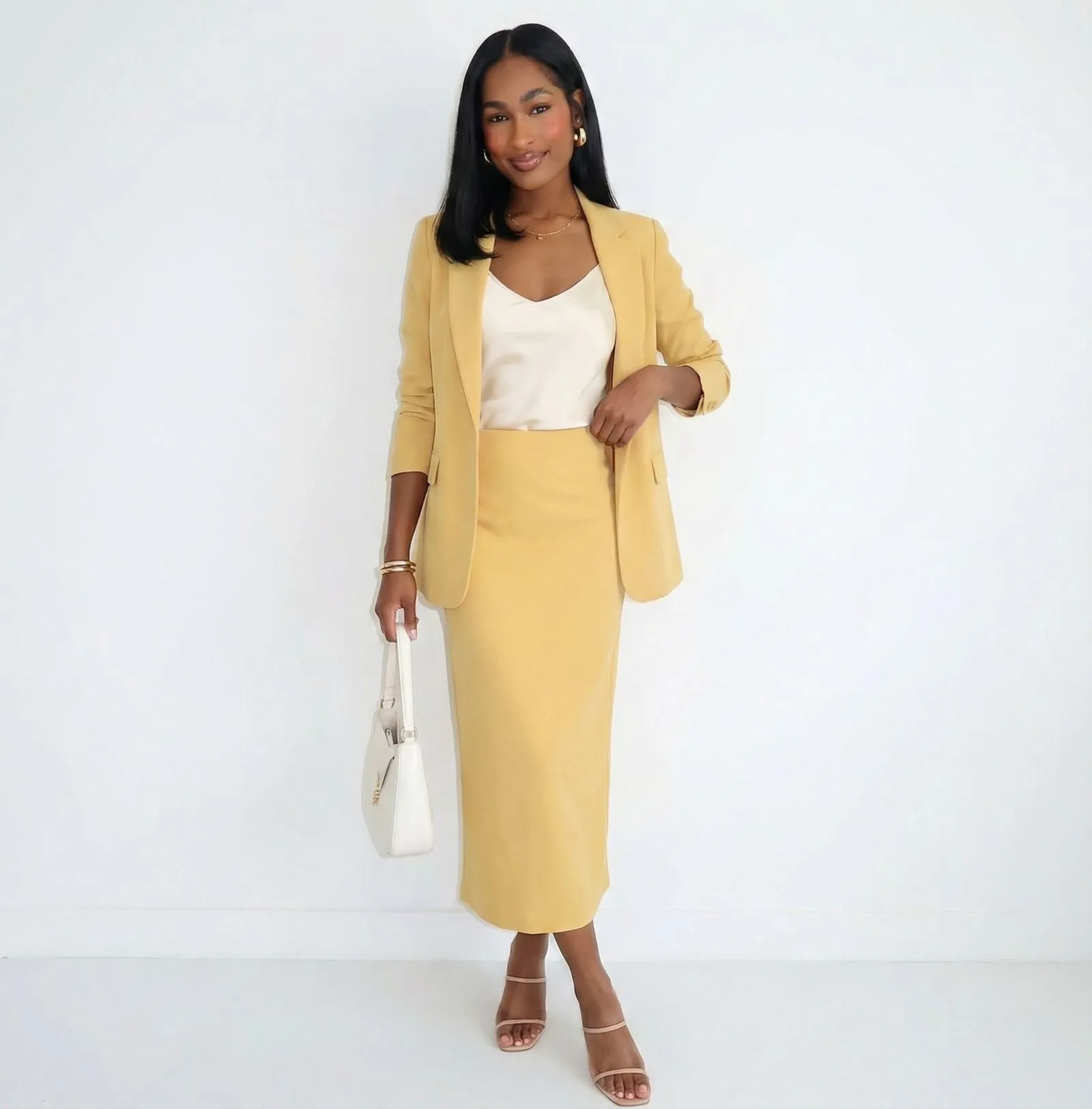 Gold jewelry and white handbag styled with yellow fabric