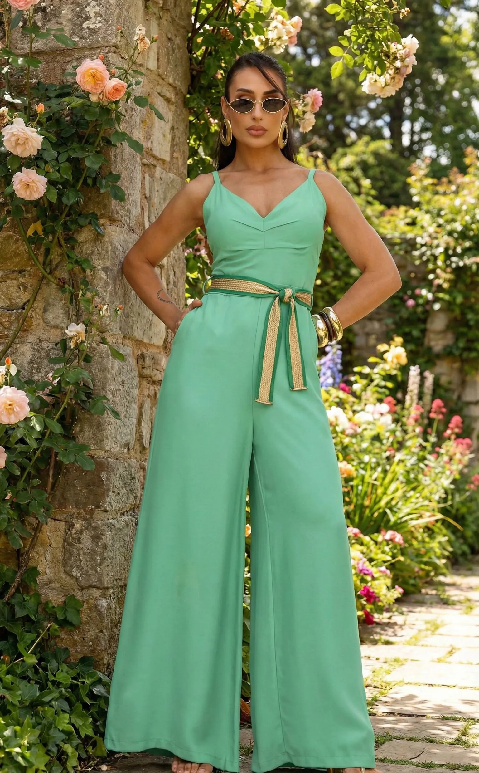 Woman wearing mint green belted jumpsuit in garden