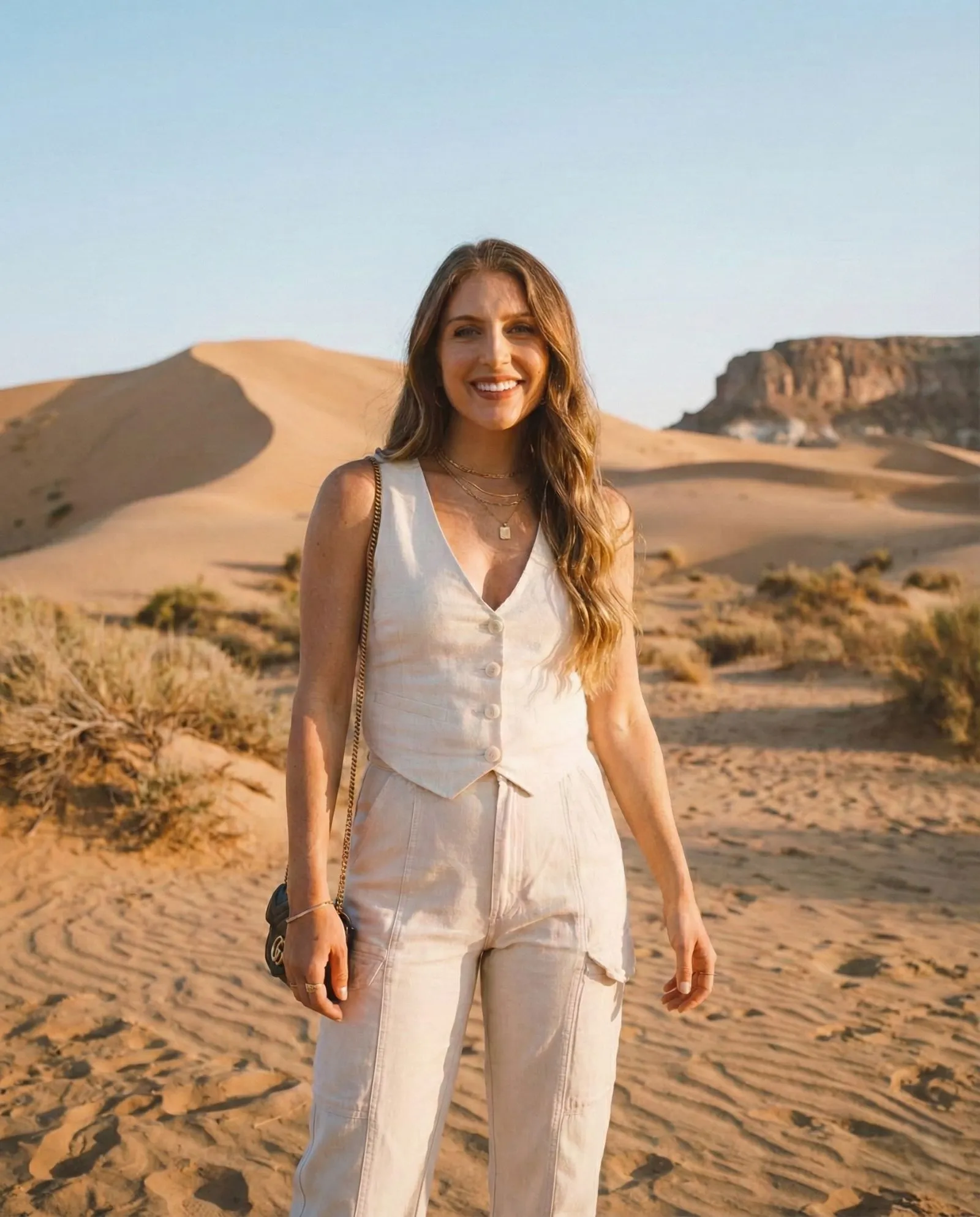 Model wearing a minimalist oatmeal linen vest and trousers set in a desert setting