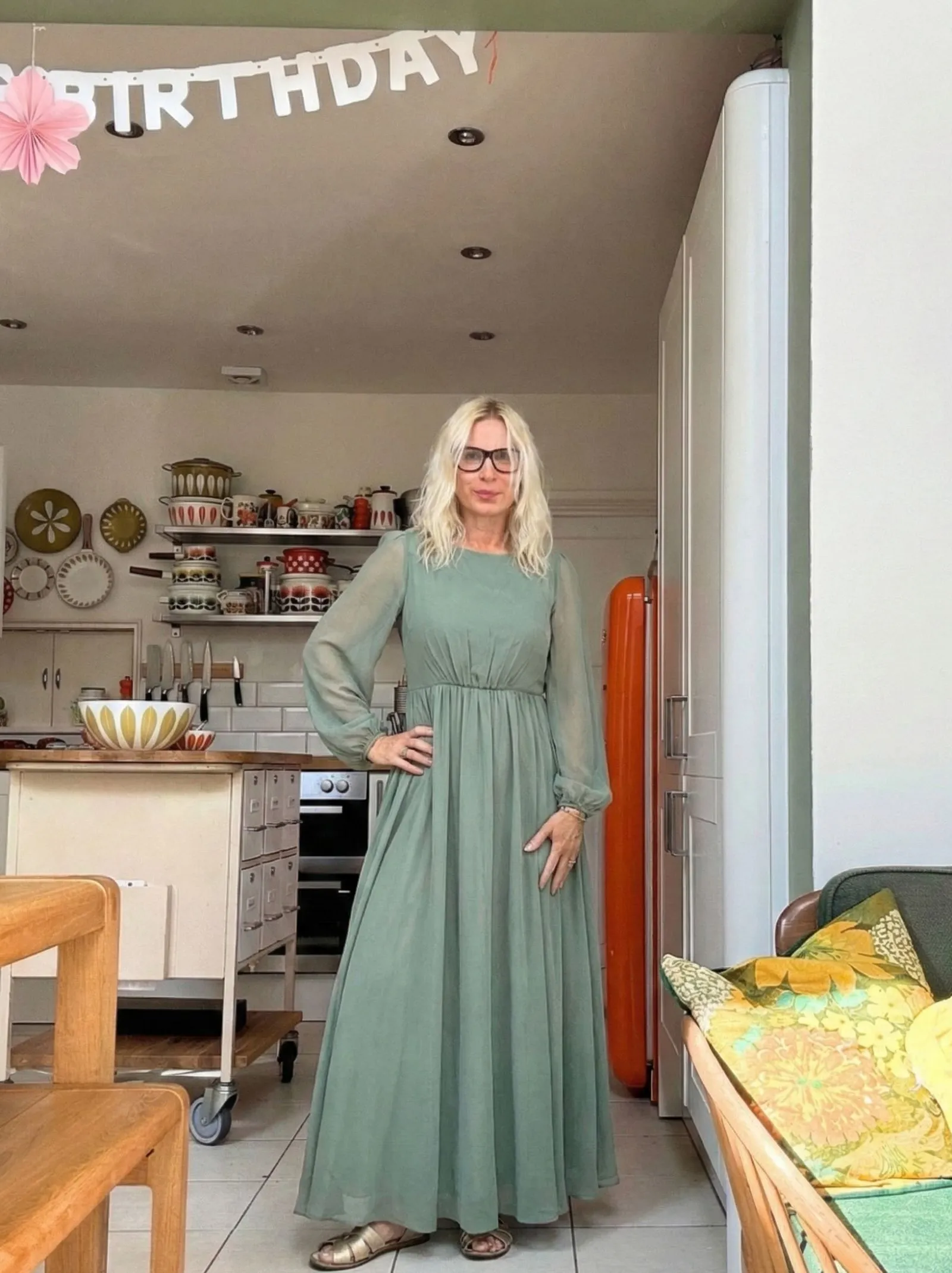 Woman over 50 wearing a sage green chiffon maxi dress with sleeves for Easter