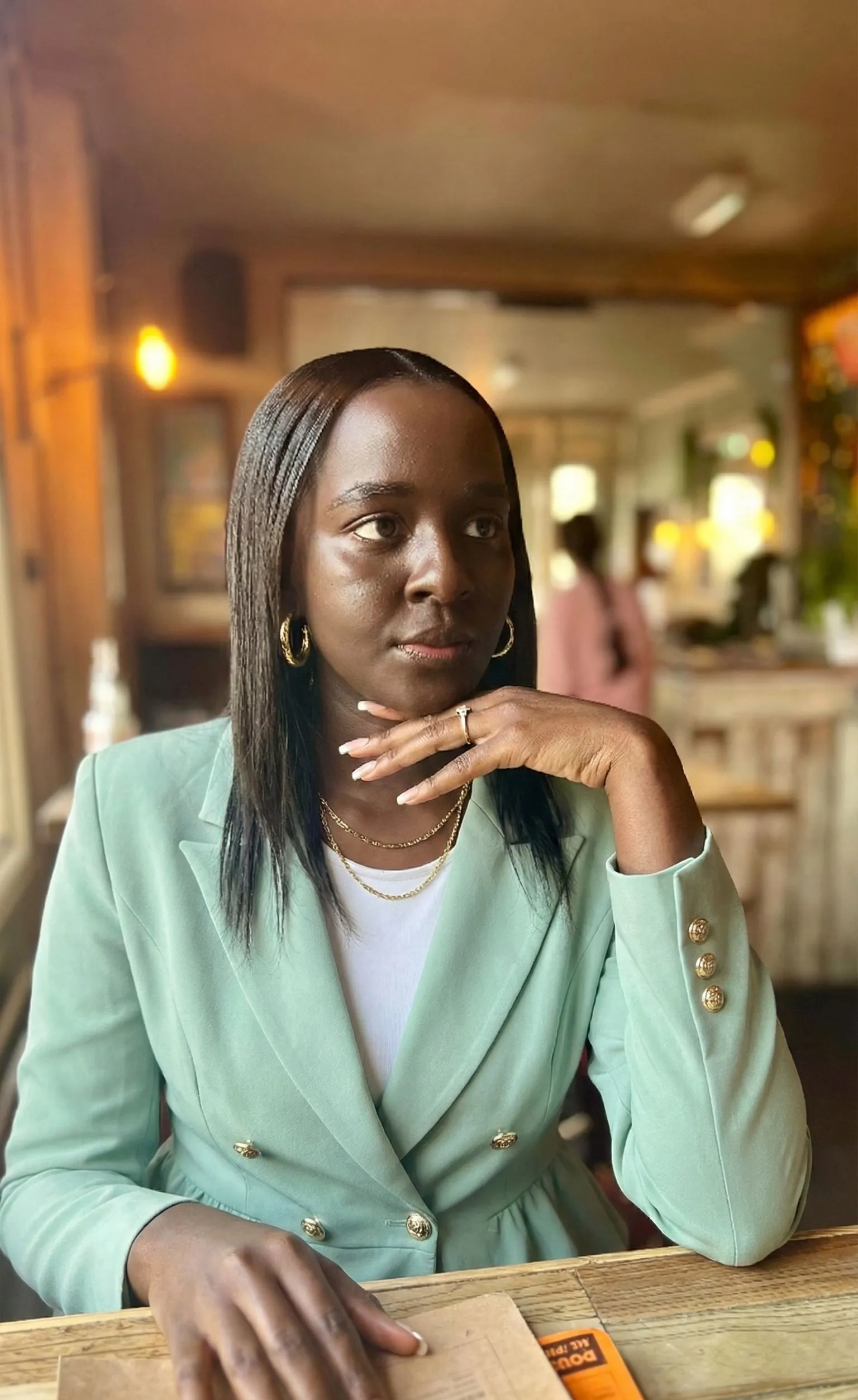 Black woman wearing a tailored soft mint peplum blazer with gold accessories