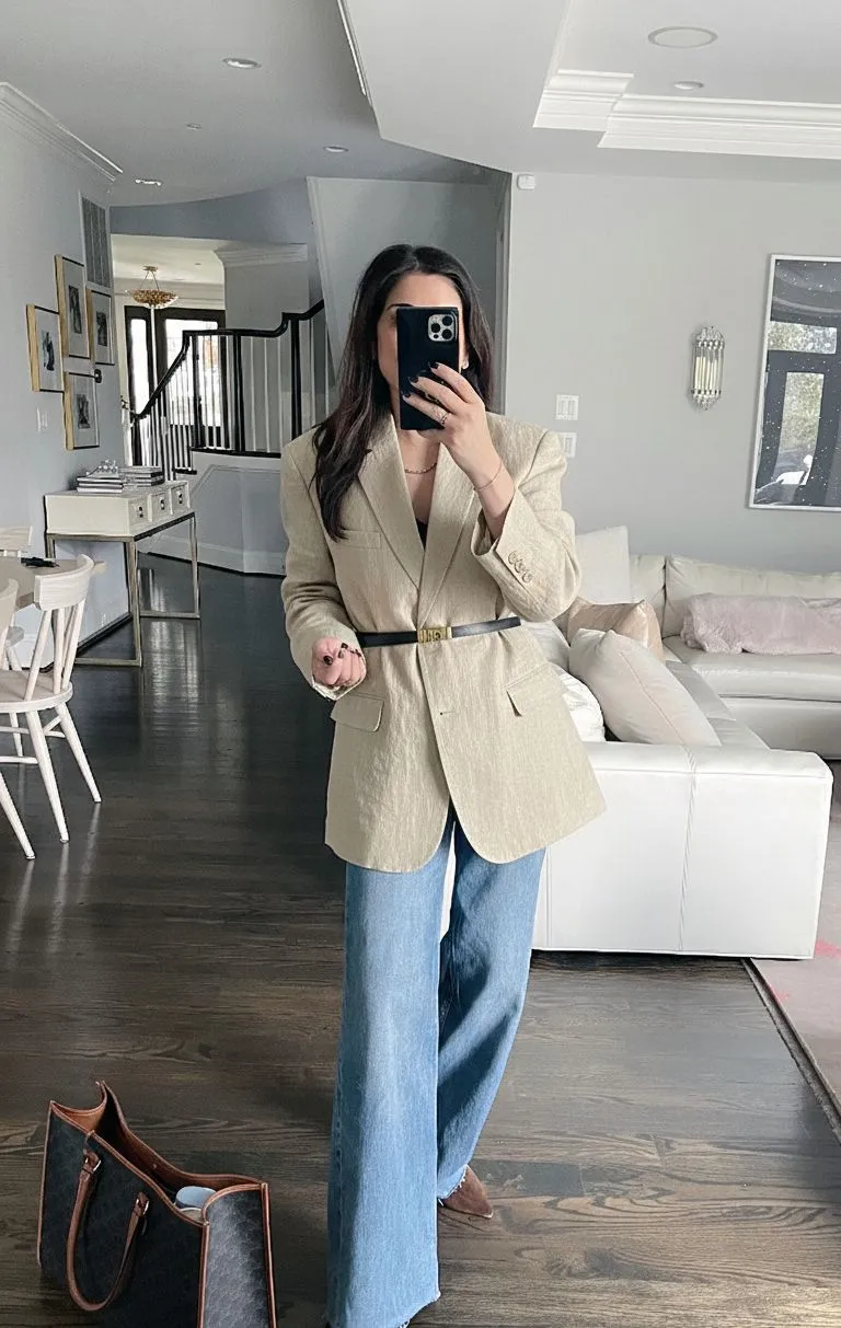 Close up of a gold belt cinching an oversized beige linen blazer