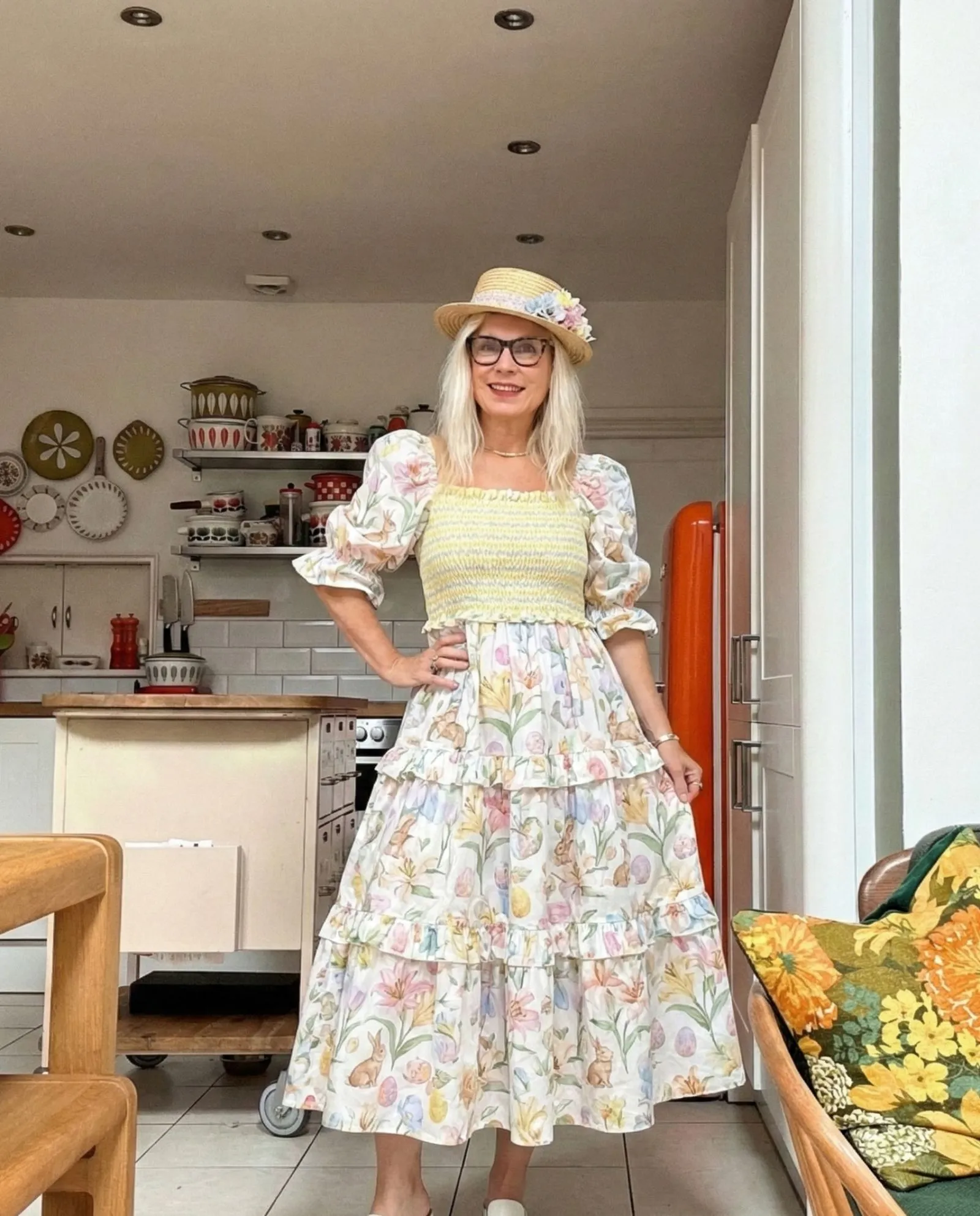 Woman over 50 wearing a chartreuse tiered midi dress in a garden setting