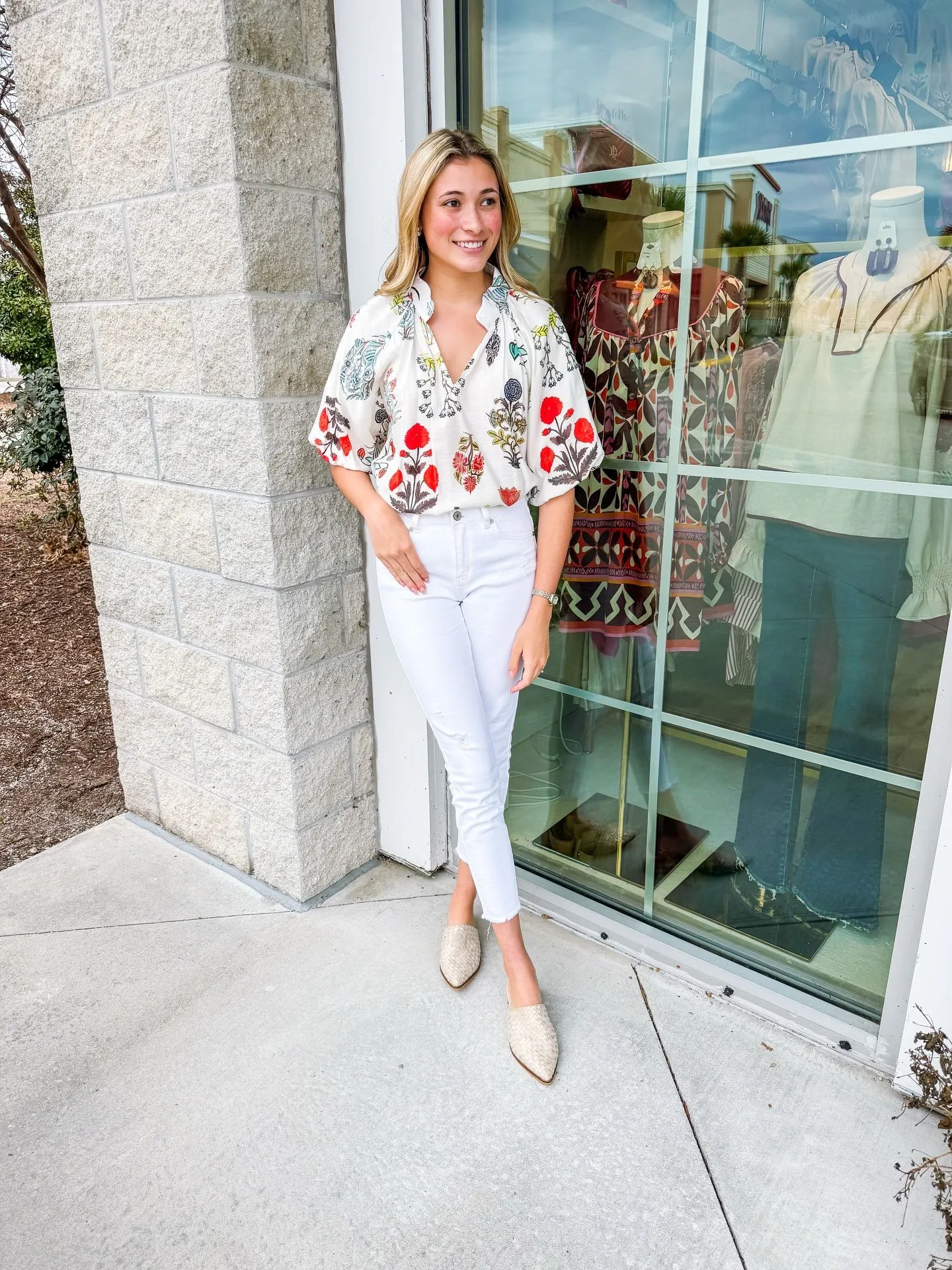 Woman wearing crisp white wide-leg jeans and a vibrant purple floral blouse for Easter brunch