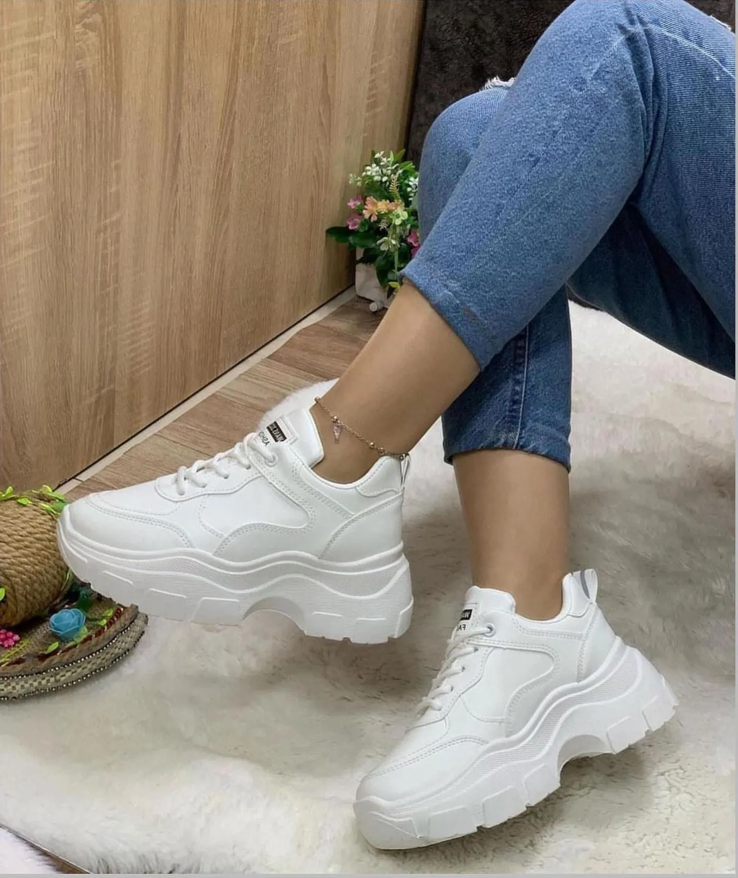 Close up of chunky white platform sneakers styled with a black satin slip dress for festival comfort