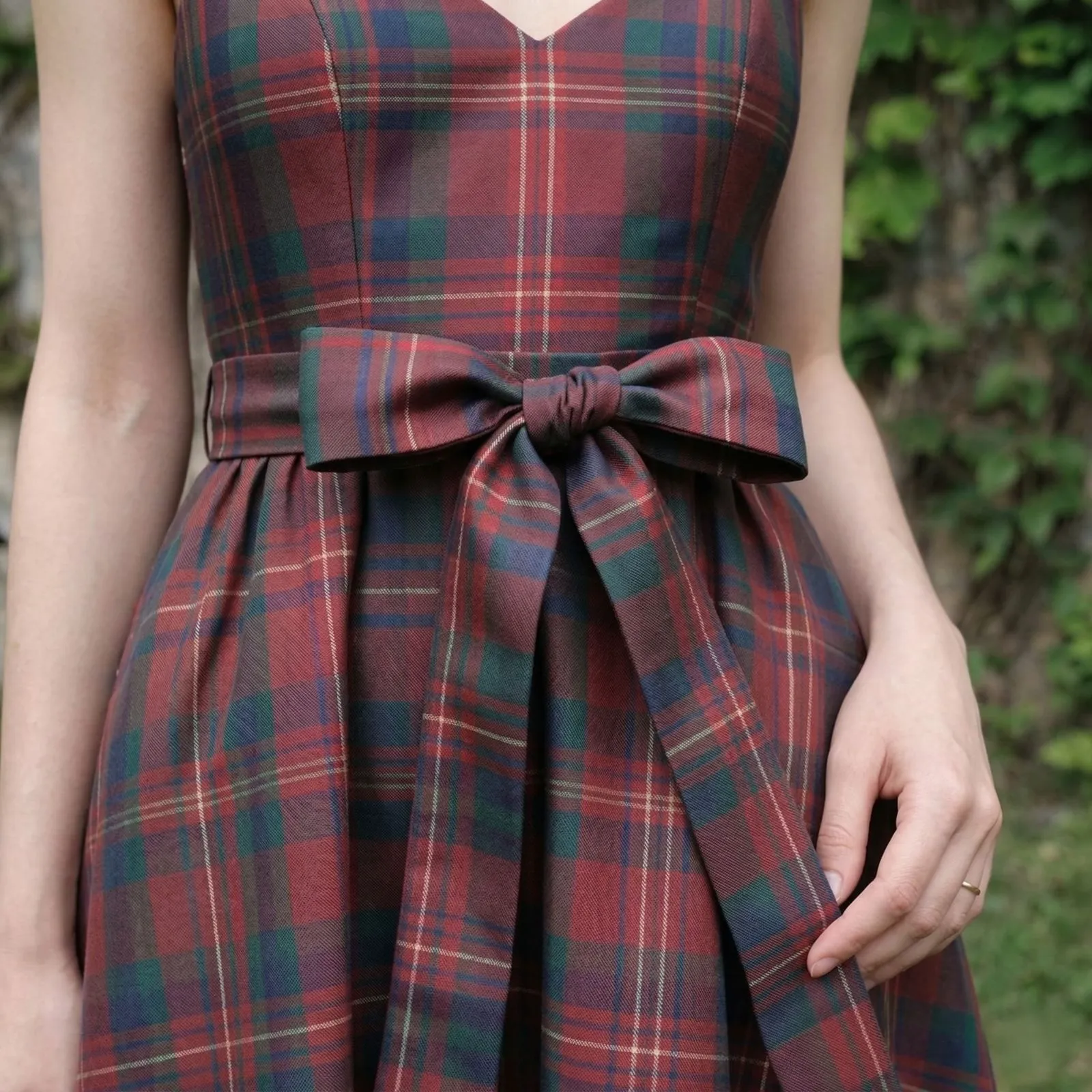 Close up detail of a forest green plaid waist tie on a fit-and-flare western dress.