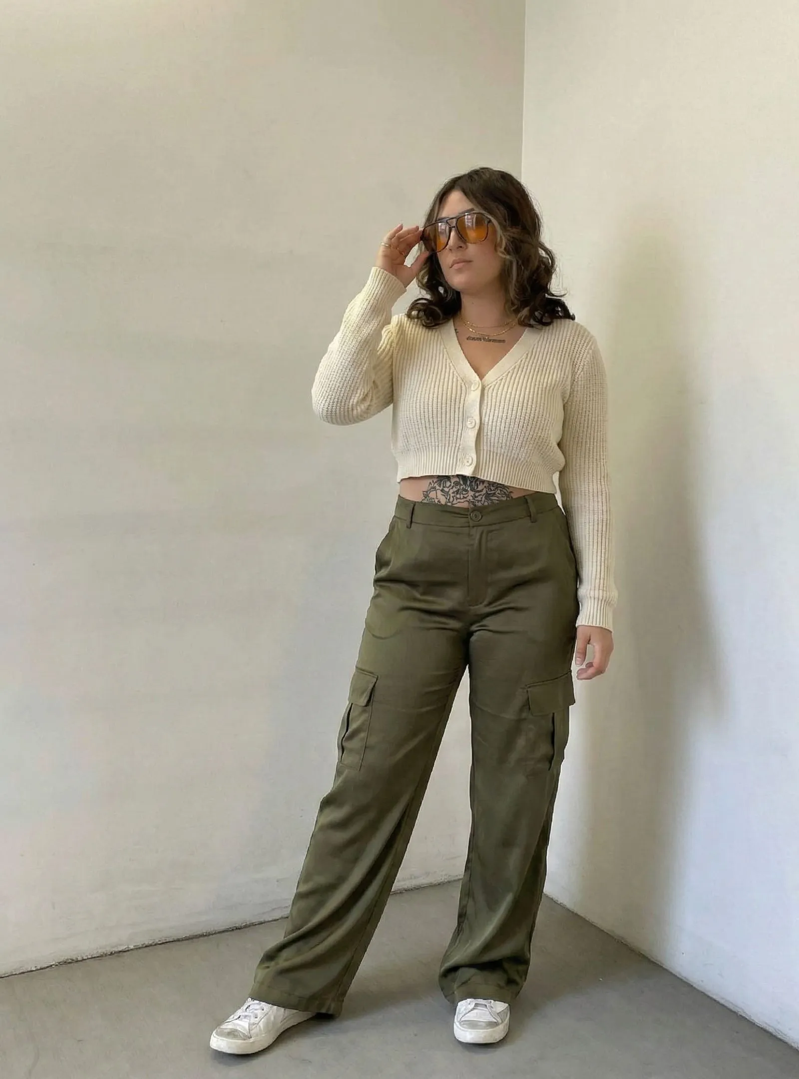 Woman wearing olive silk cargo pants and cream cropped cardigan on a Los Angeles street