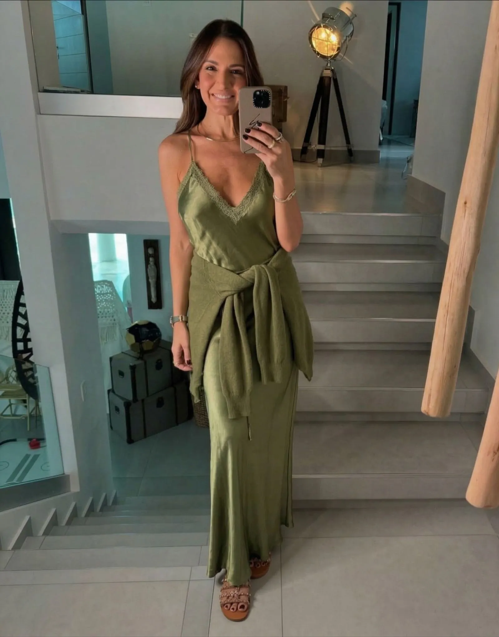 Woman with cashmere sweater tied over olive silk slip dress