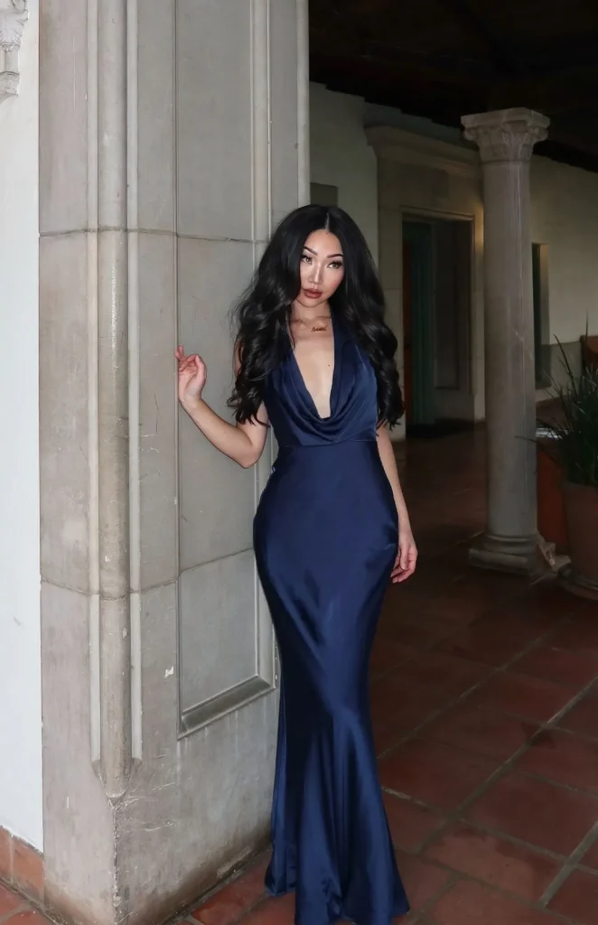 Detailed view of a navy silk slip dress hem on stone floor.