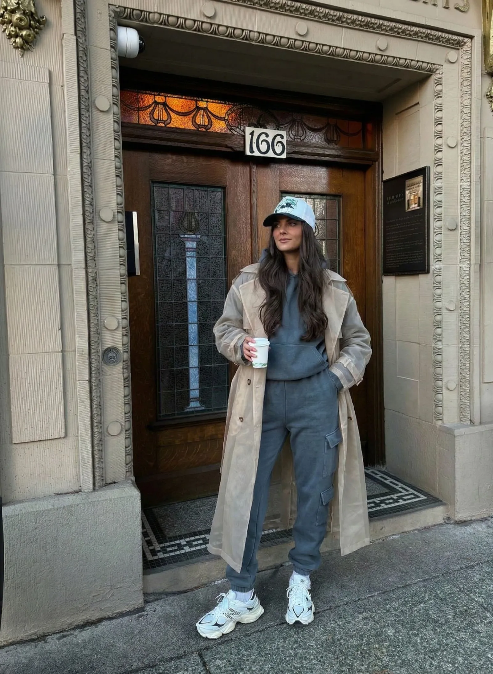 Woman wearing slate grey monochromatic sweatsuit and sheer trench coat in Los Angeles
