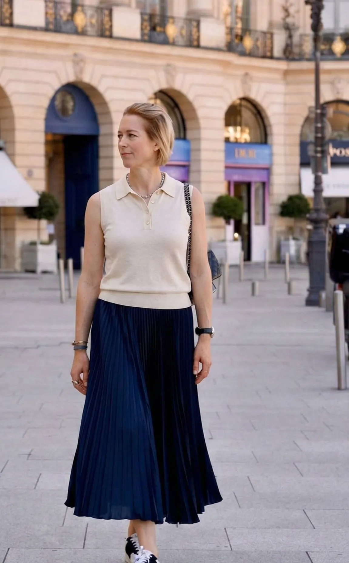 Woman wearing a sleeveless knit polo and pleated midi skirt in New York City