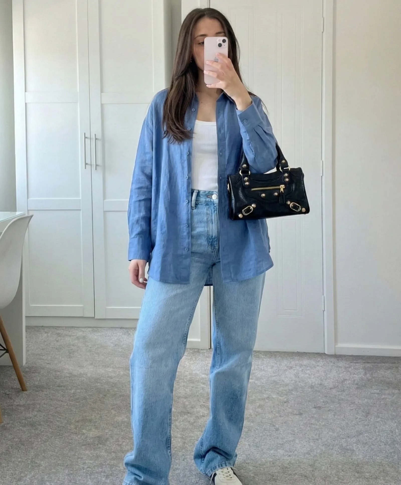 Woman wearing oversized blue linen shirt open over white ribbed tank top street style