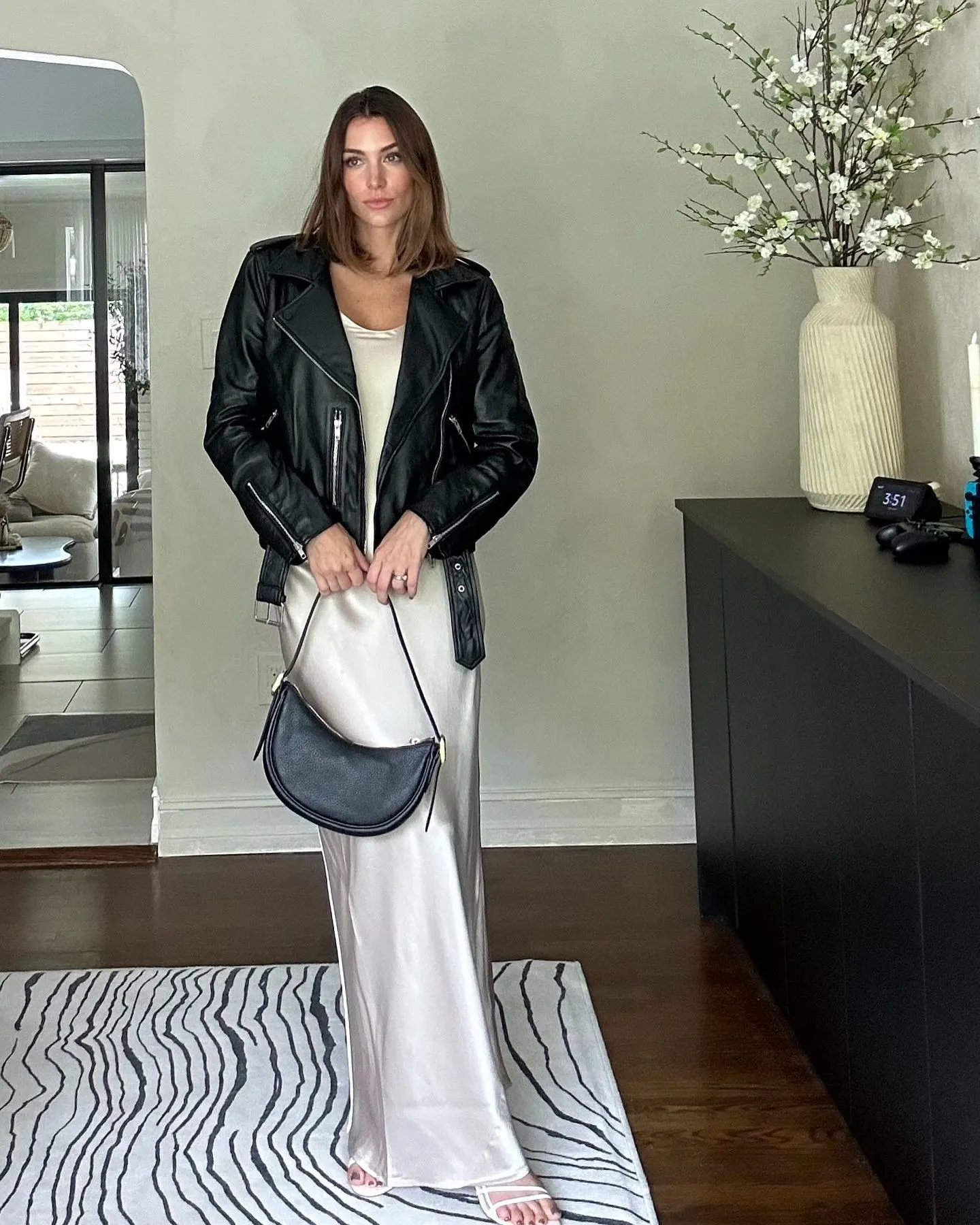 Woman wearing champagne silk slip dress and black leather moto jacket on Los Angeles street at dusk