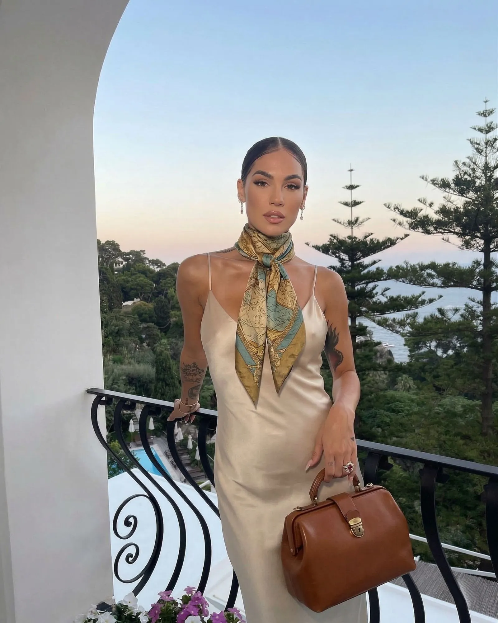 Woman in a champagne silk slip dress wearing a vintage scarf and carrying a top-handle bag.