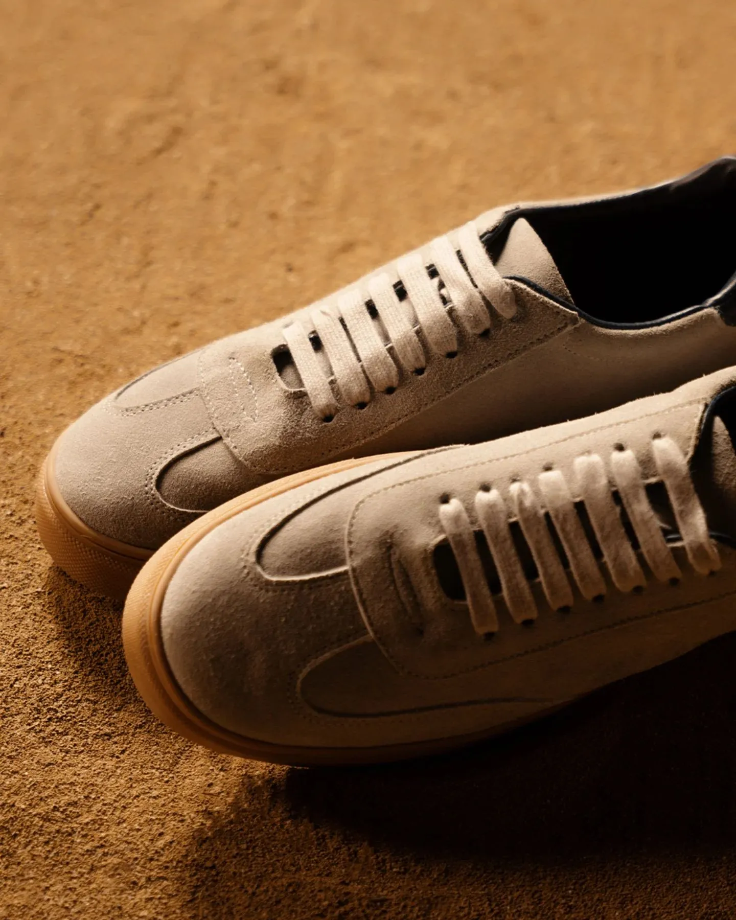 Close up of matte suede platform sneakers paired with a silk skirt and cashmere sweater