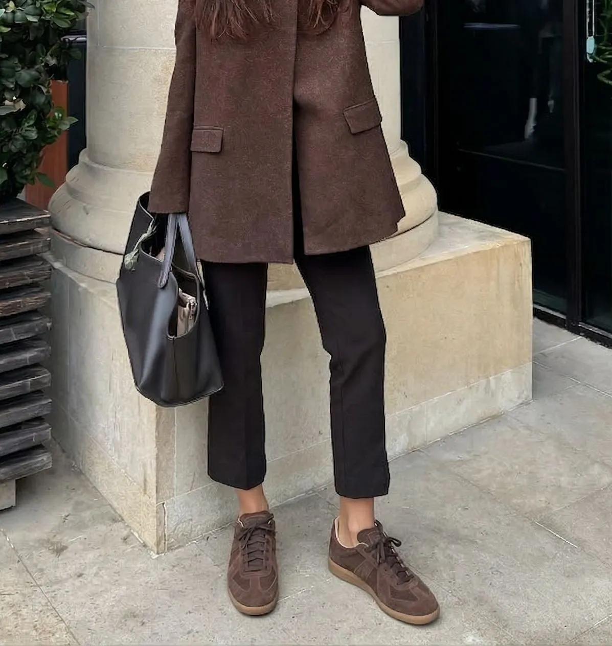 Woman wearing oversized brown blazer with retro suede sneakers in Paris