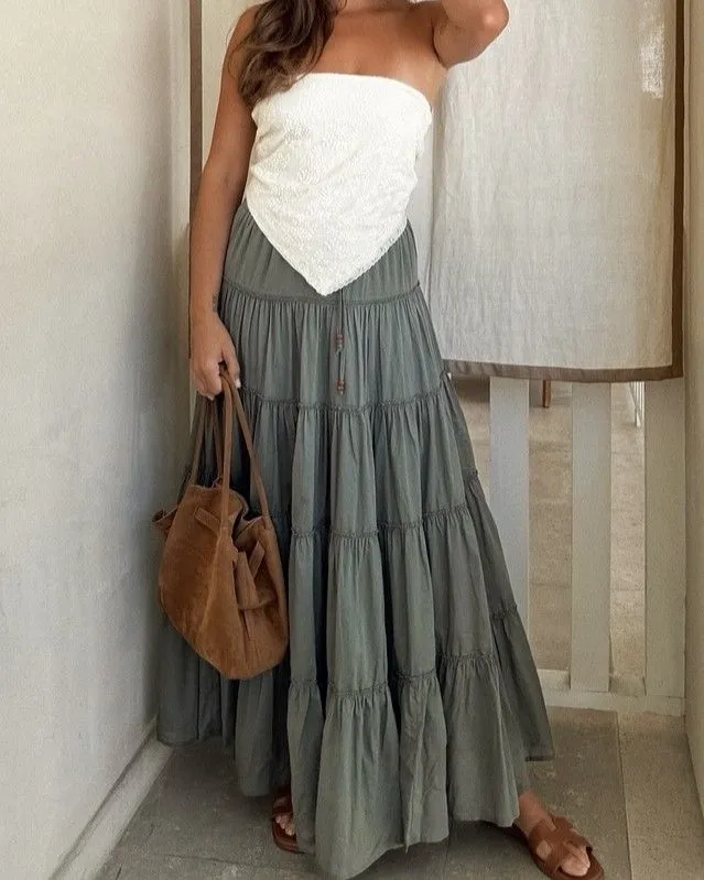 Close up of a sage green tiered maxi skirt styled with vintage leather cowboy boots