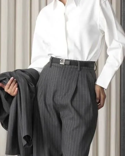 Detail of a silk blouse tucked into high-waisted trousers.