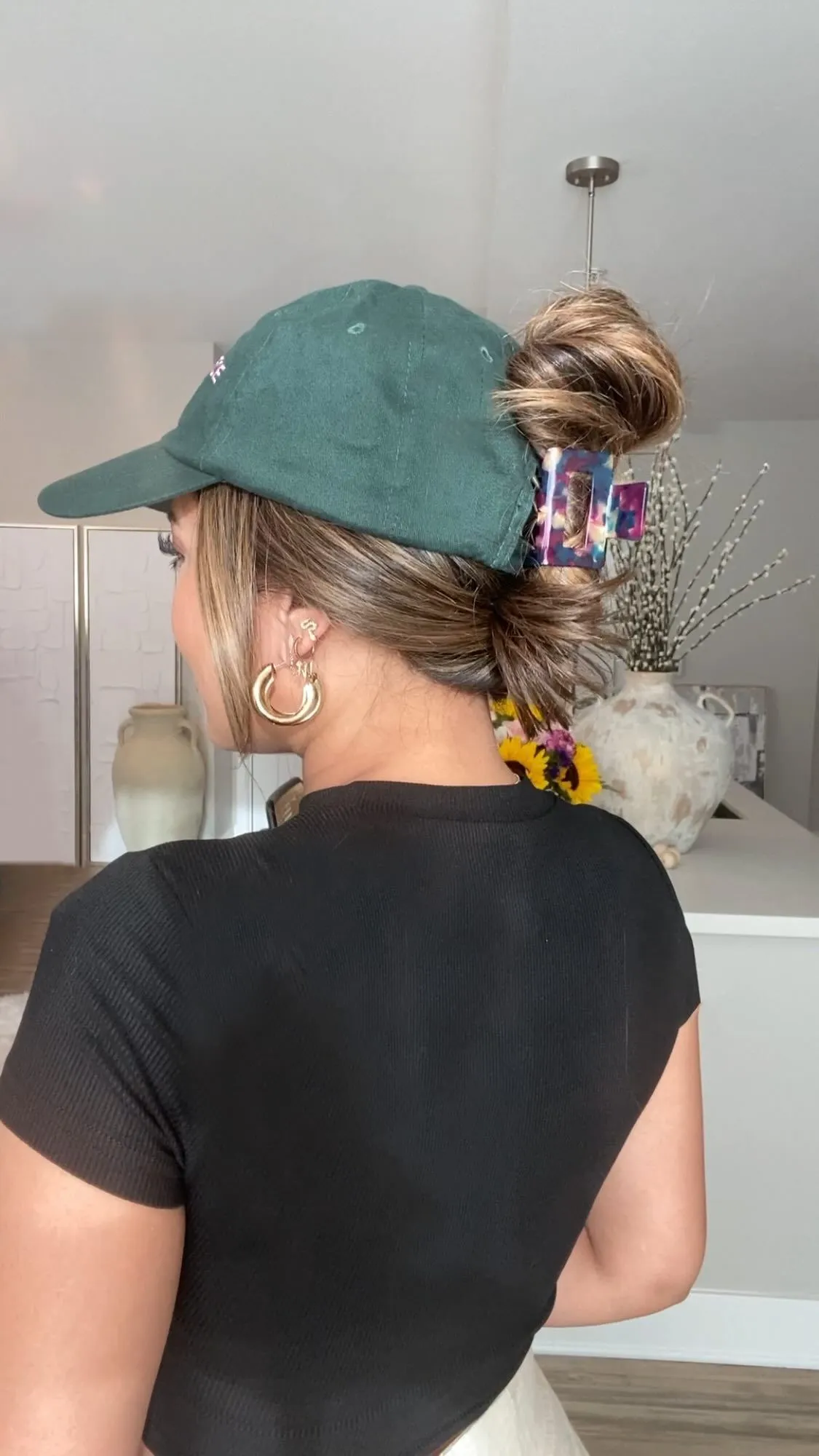 Low messy bun hairstyle with a tan satin baseball cap