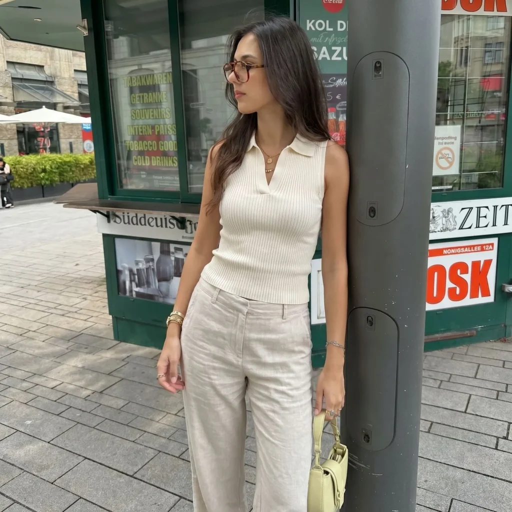 Woman wearing a cream ribbed sleeveless polo with linen trousers for a summer old money look