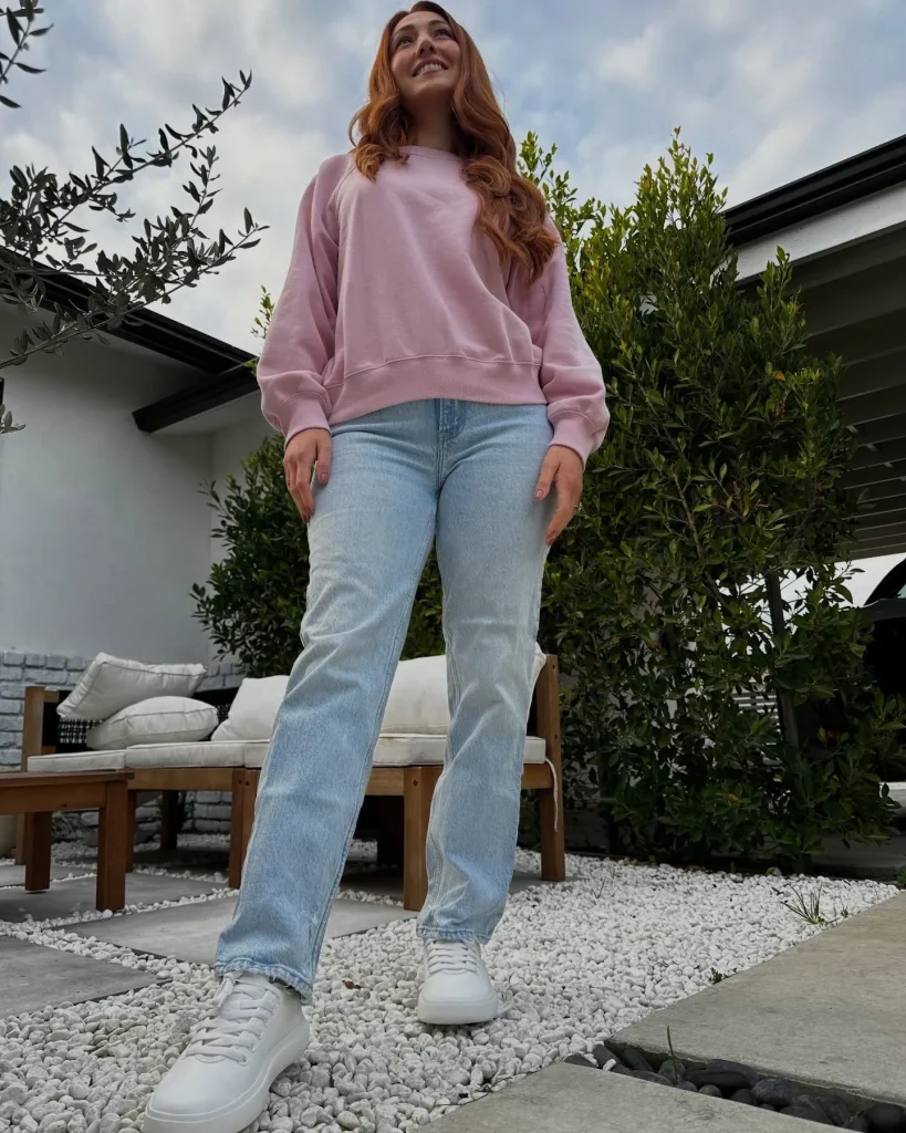 Curvy model wearing light-wash flared jeans and white high-top canvas sneakers for a country concert.