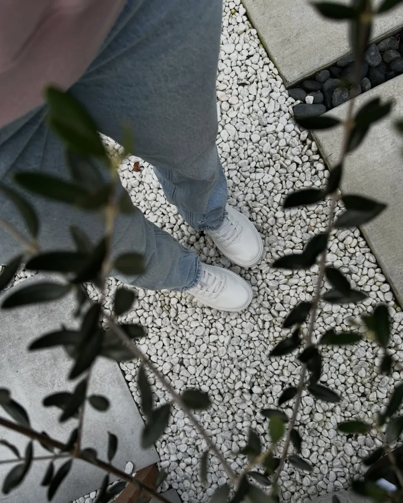 Close-up of light-wash flared jeans styled with white canvas high-top sneakers.