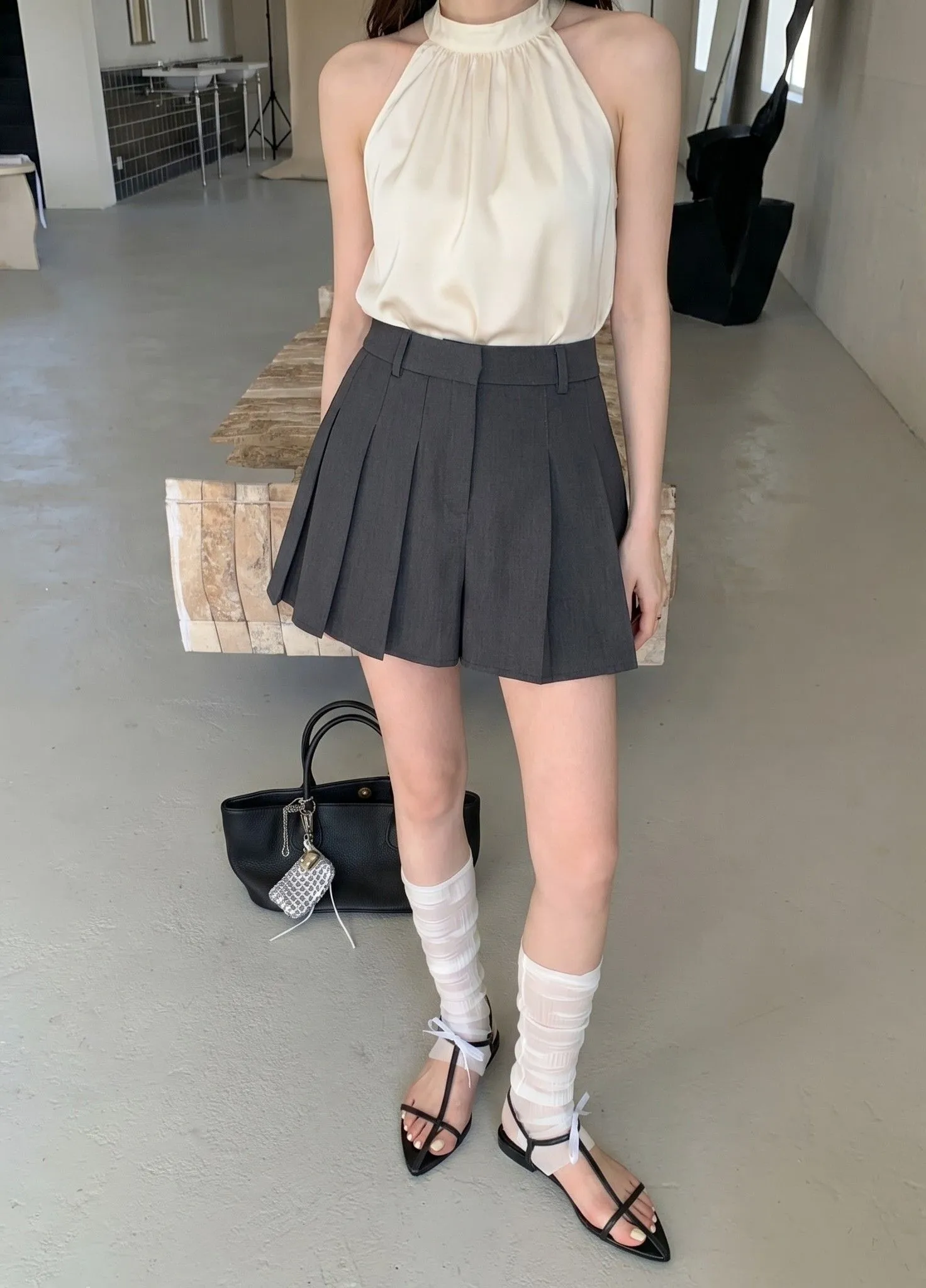 Close up of a tailored high-rise pleated skort paired with a cream silk halter top